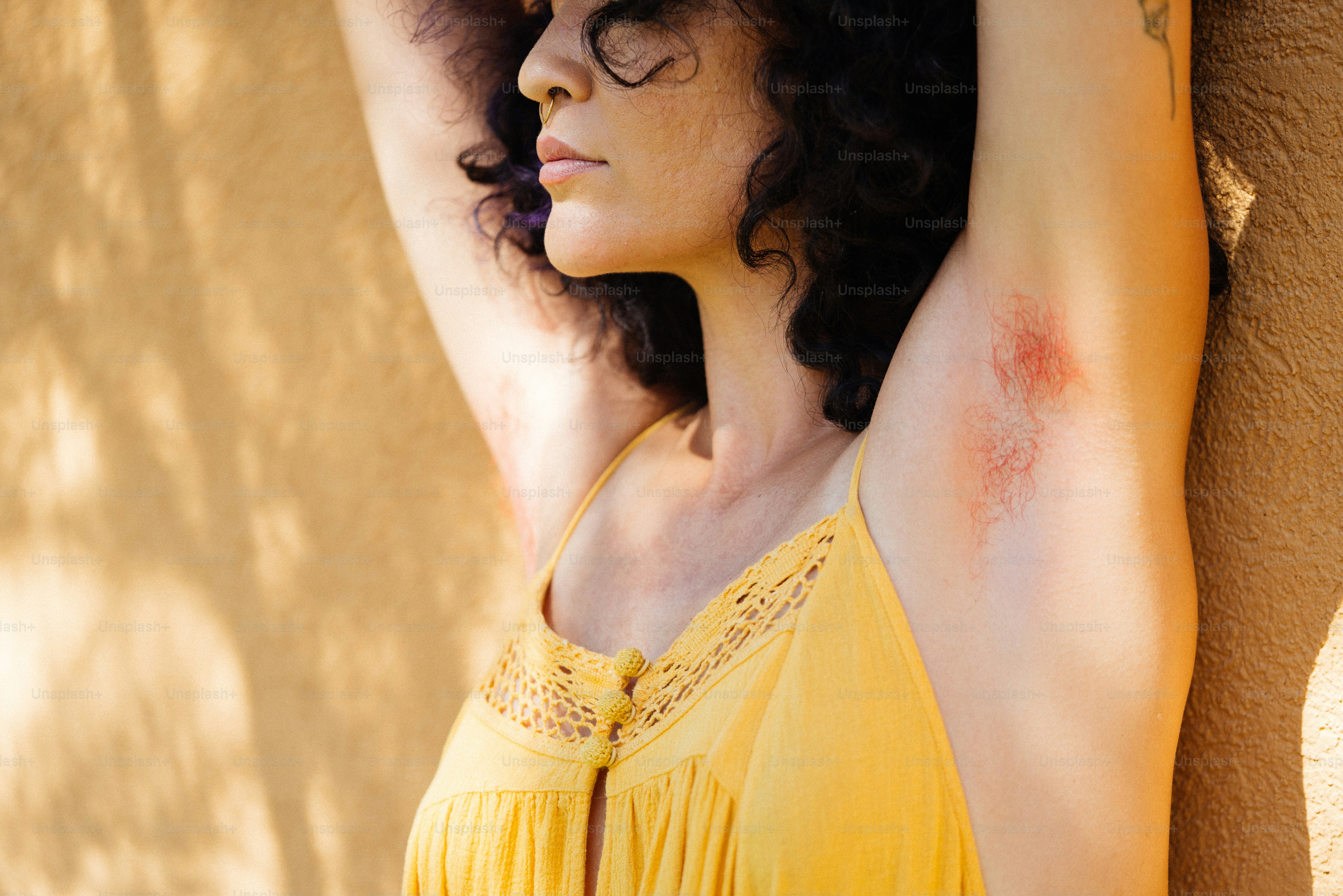 a woman in a yellow dress leaning against a wall