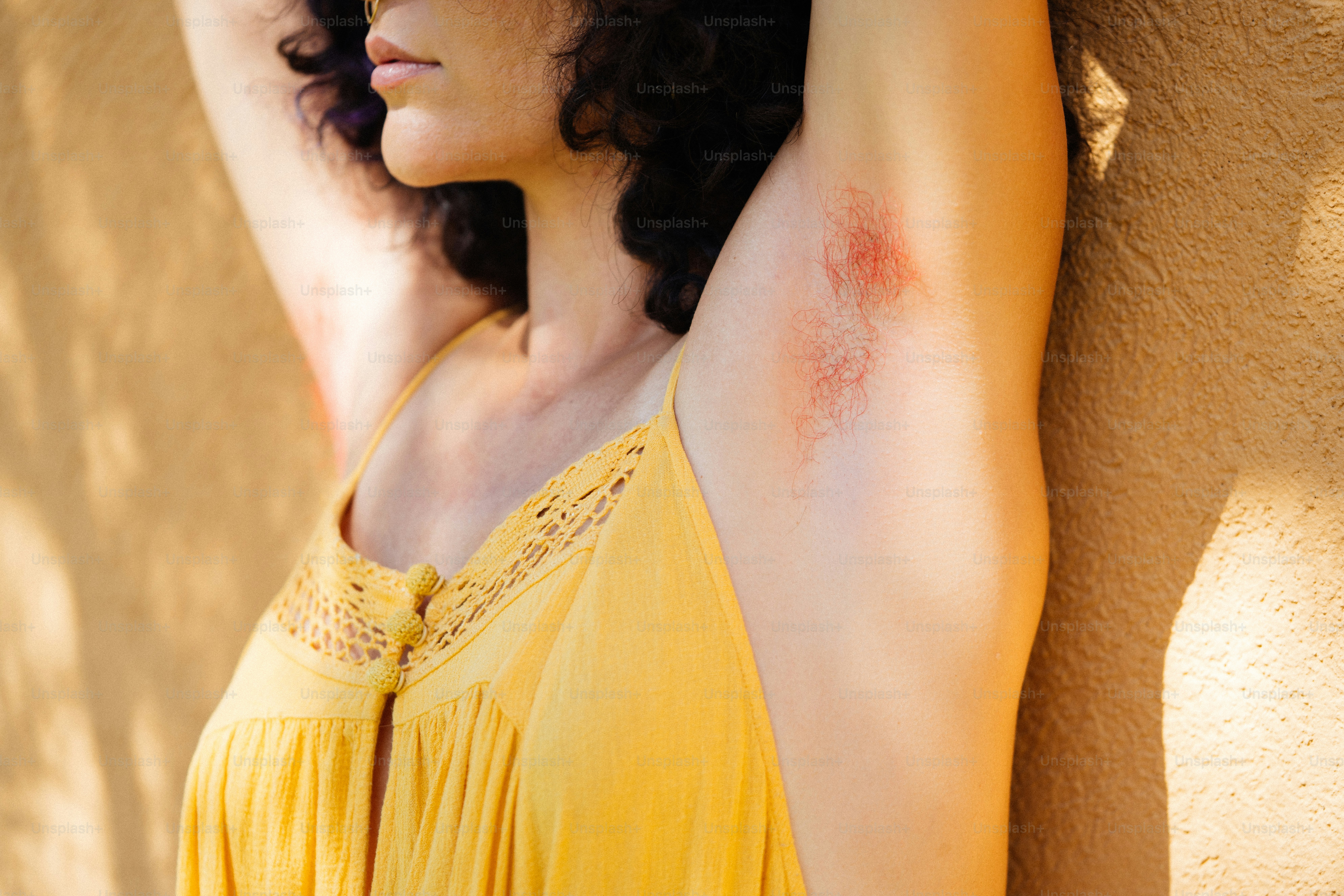a woman in a yellow dress leaning against a wall
