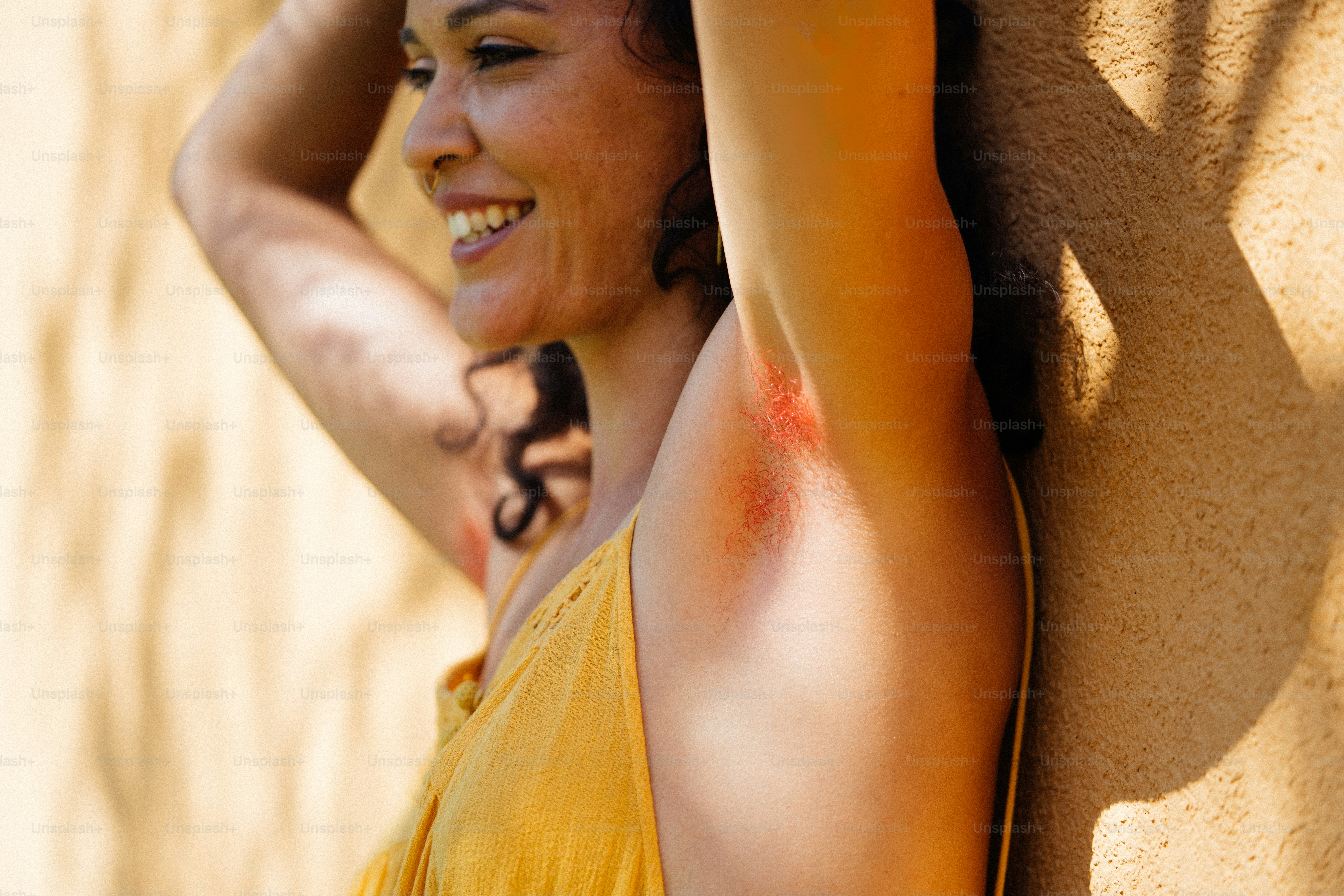 a woman in a yellow shirt leaning against a wall