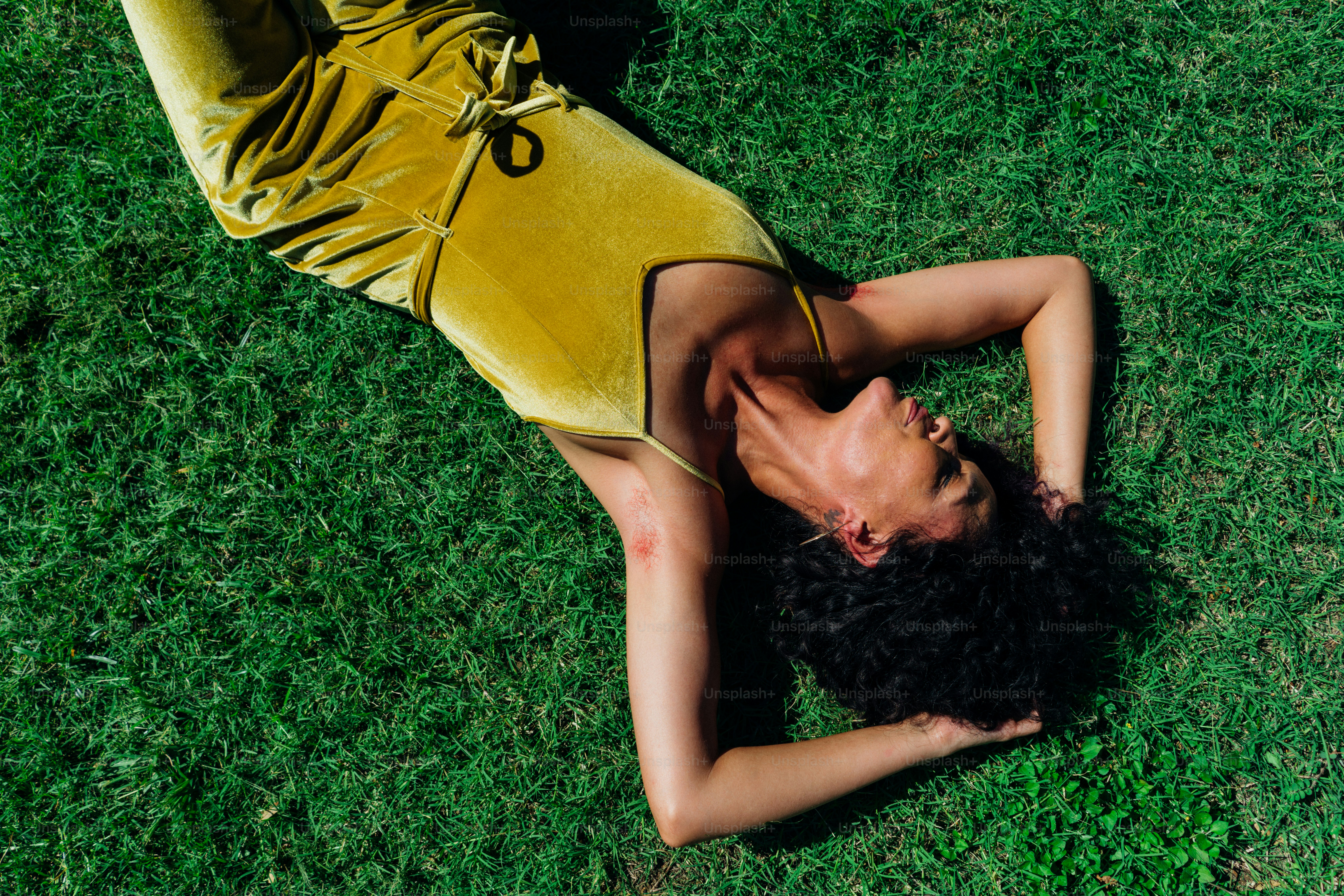 a woman in a yellow dress laying on the grass