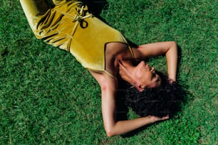 uma mulher em um vestido amarelo deitado na grama