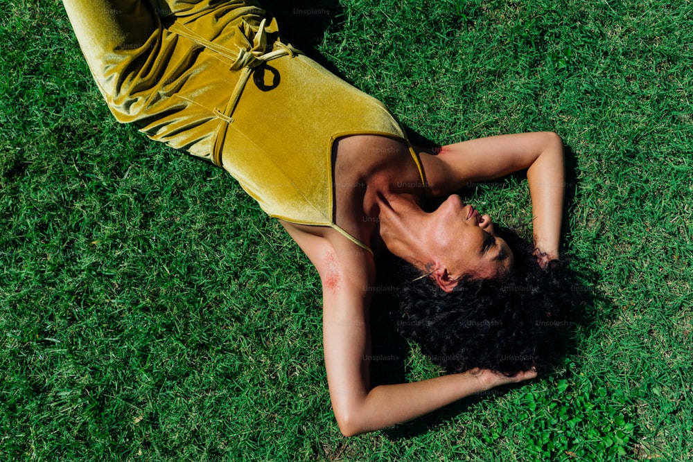 a woman in a yellow dress laying on the grass