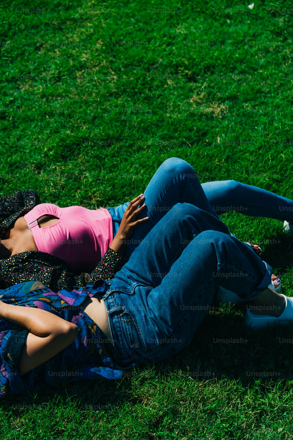 a couple of people laying on top of a lush green field