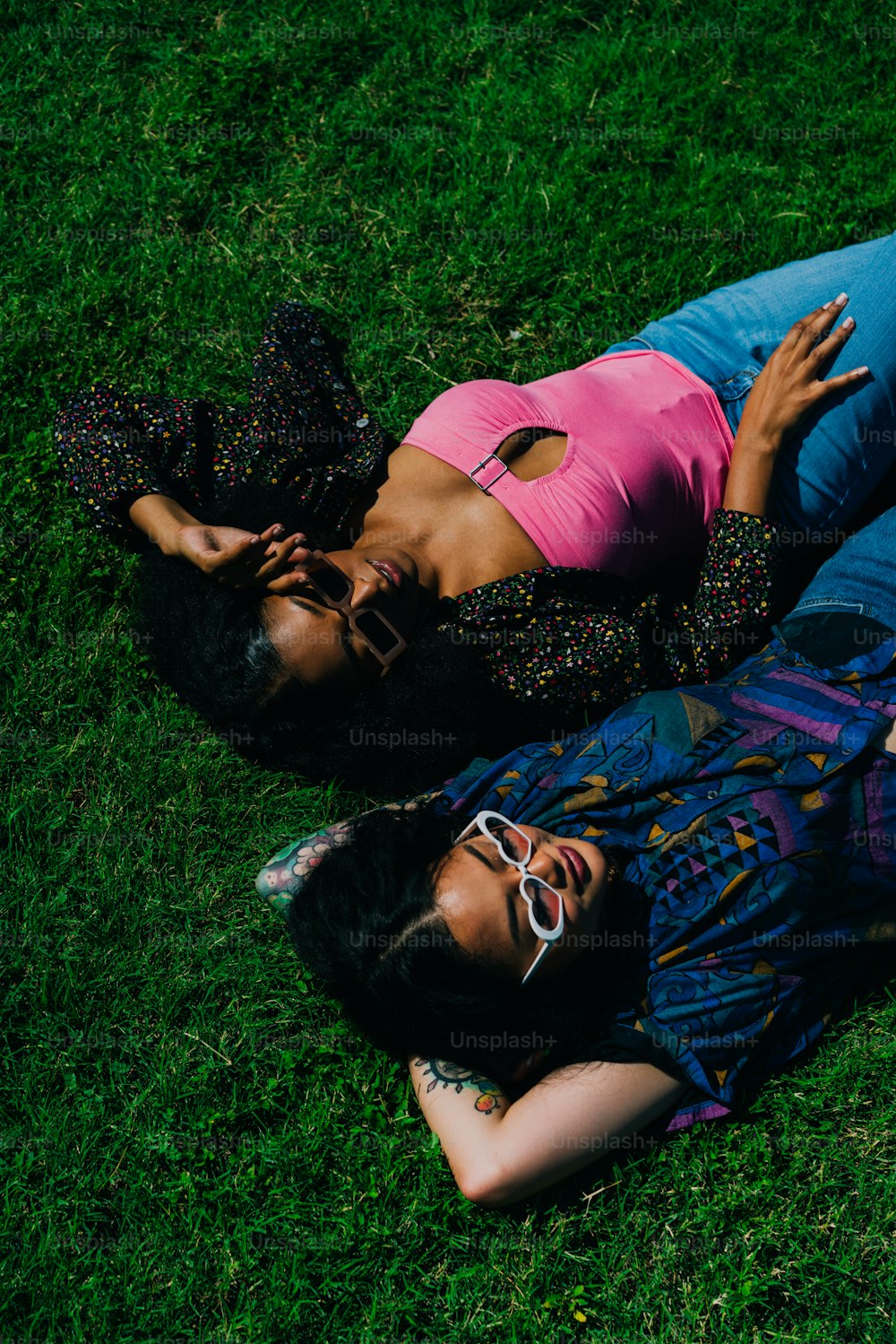 a couple of people laying on top of a lush green field