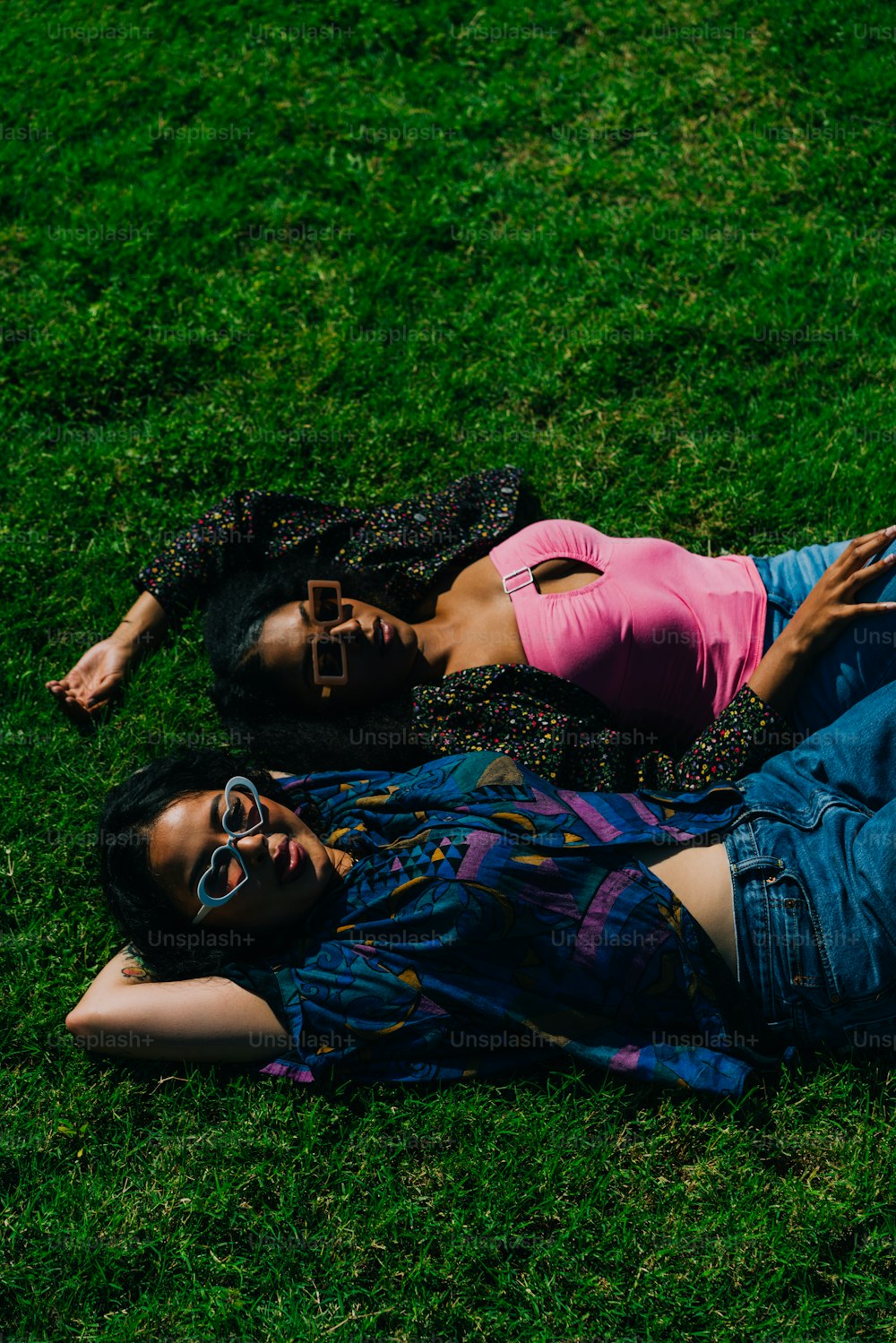 a couple of people laying on top of a lush green field