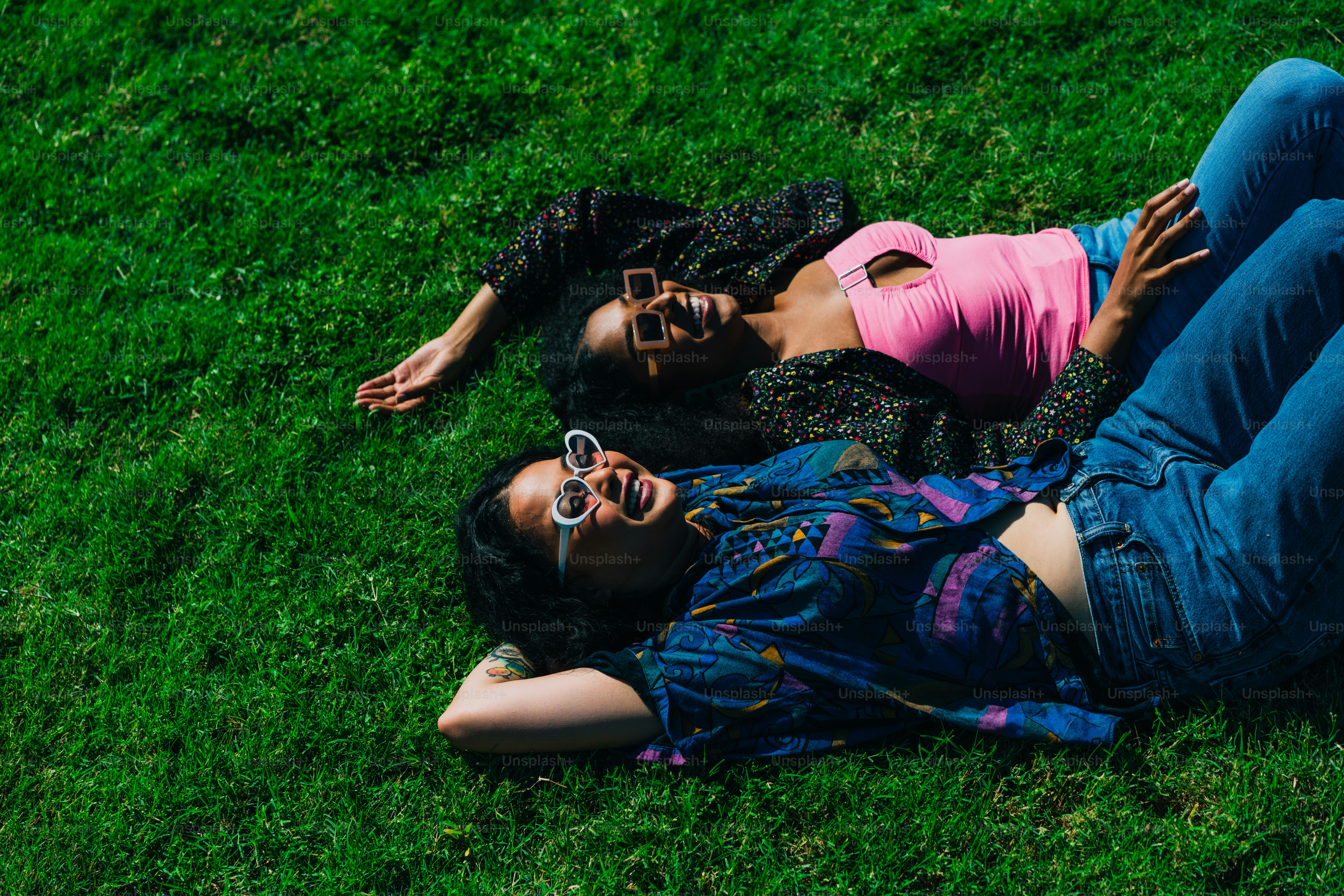 a couple of people laying on top of a lush green field