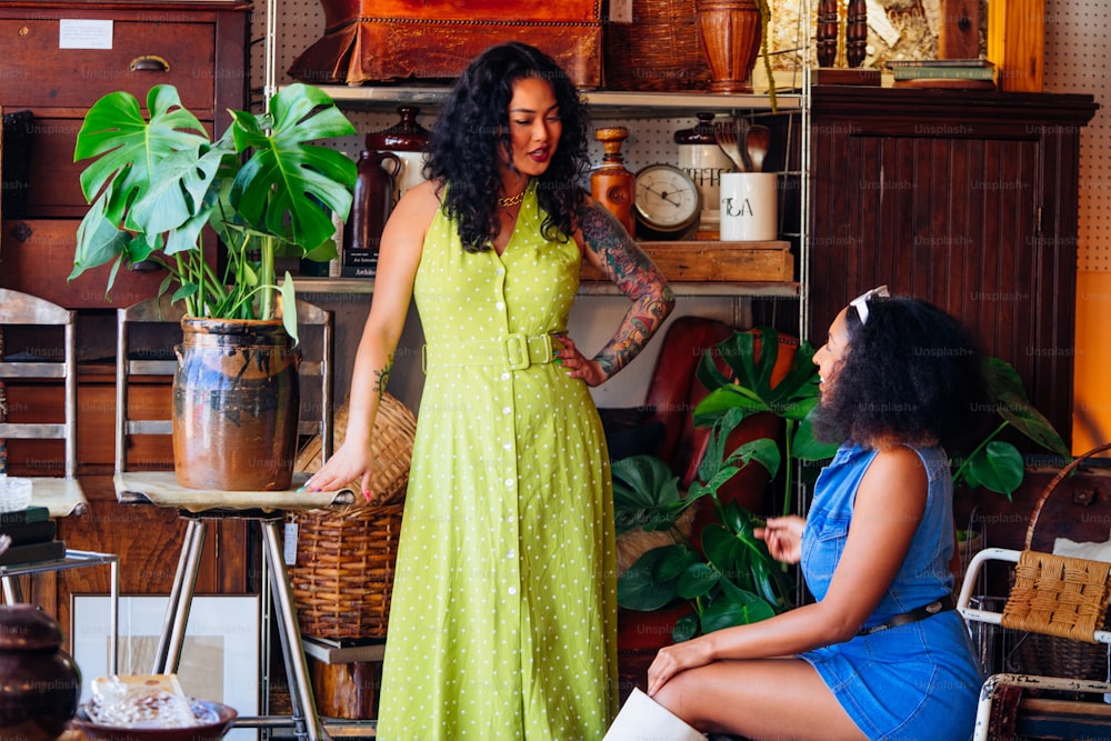 a woman in a green dress standing next to a woman in a blue dress