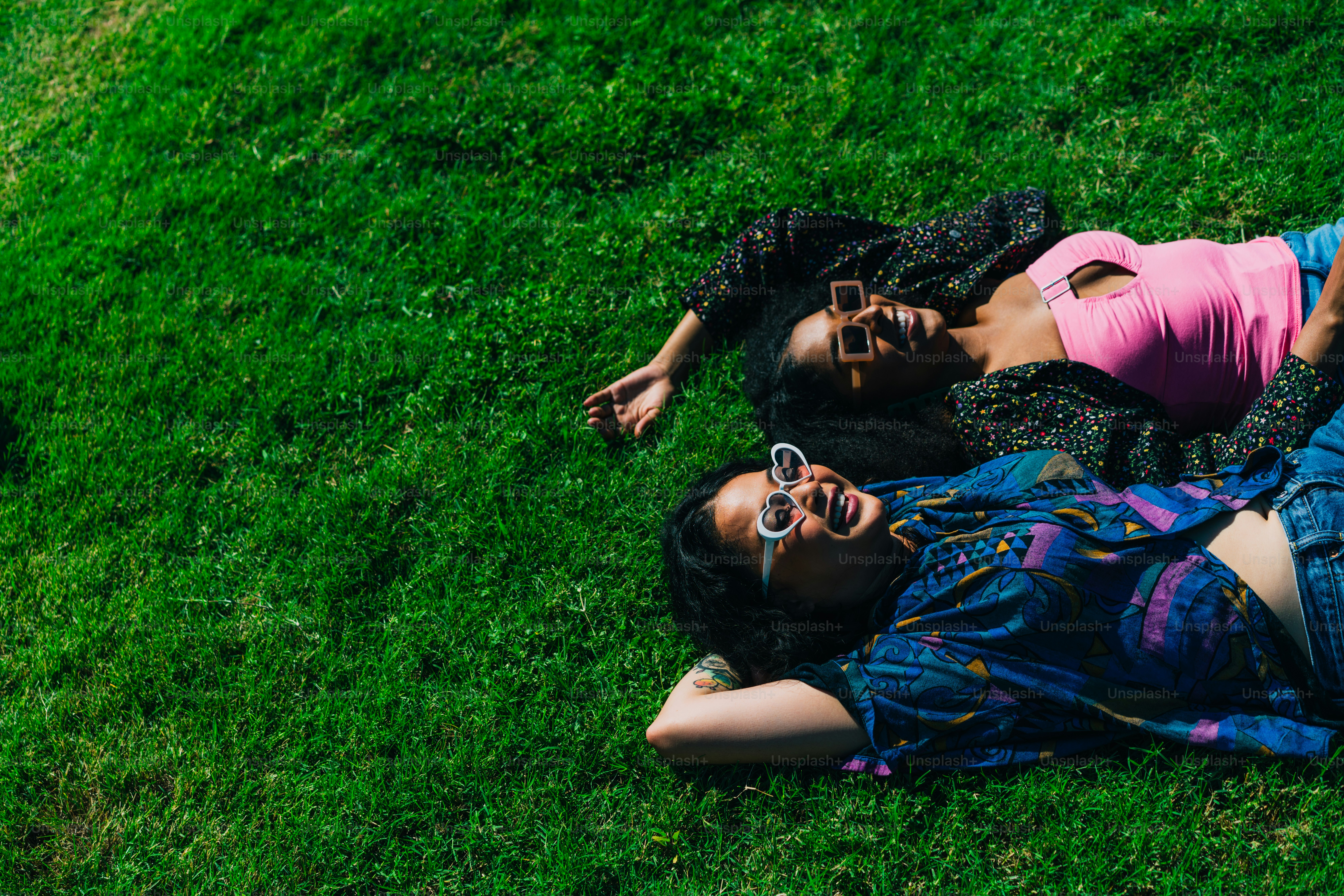 a couple of people laying on top of a lush green field