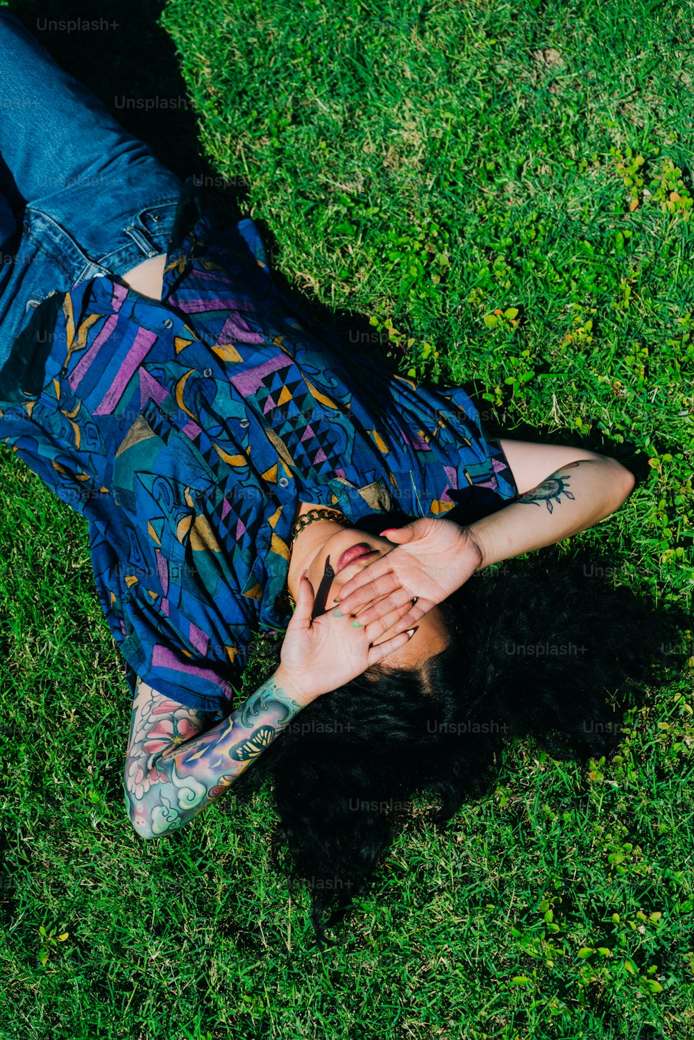 a woman laying in the grass with her arms around her body