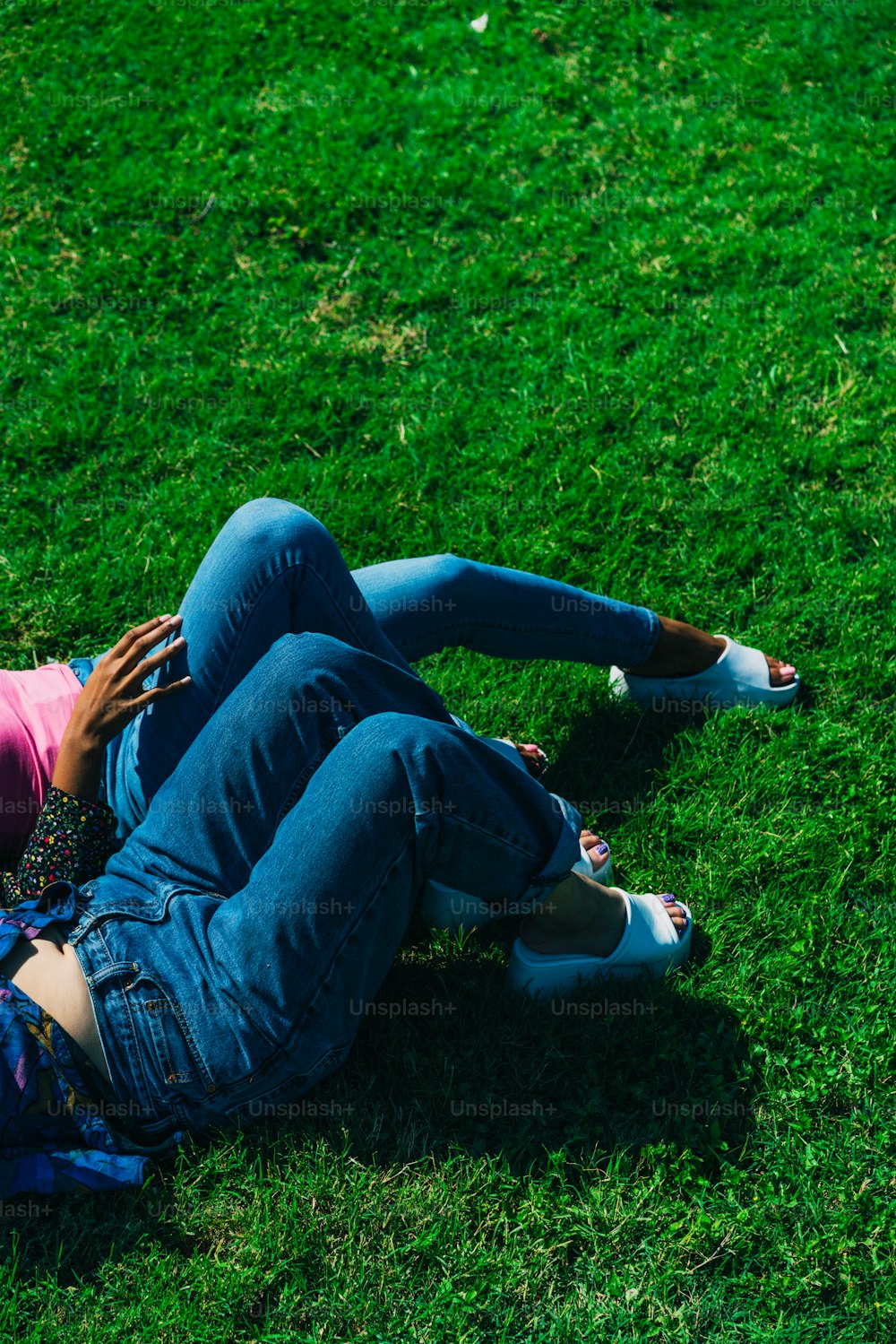 a woman laying on top of a lush green field