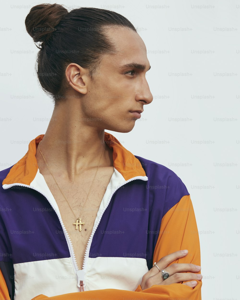 Un hombre con los brazos cruzados con una chaqueta naranja y púrpura