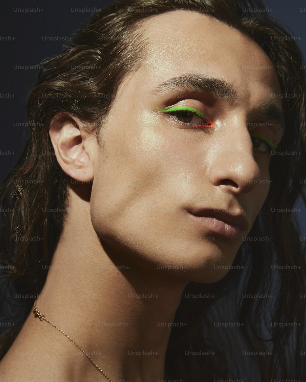 a man with green and red eyeliners on his face