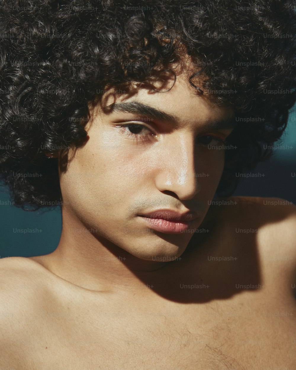 a close up of a shirtless man with curly hair