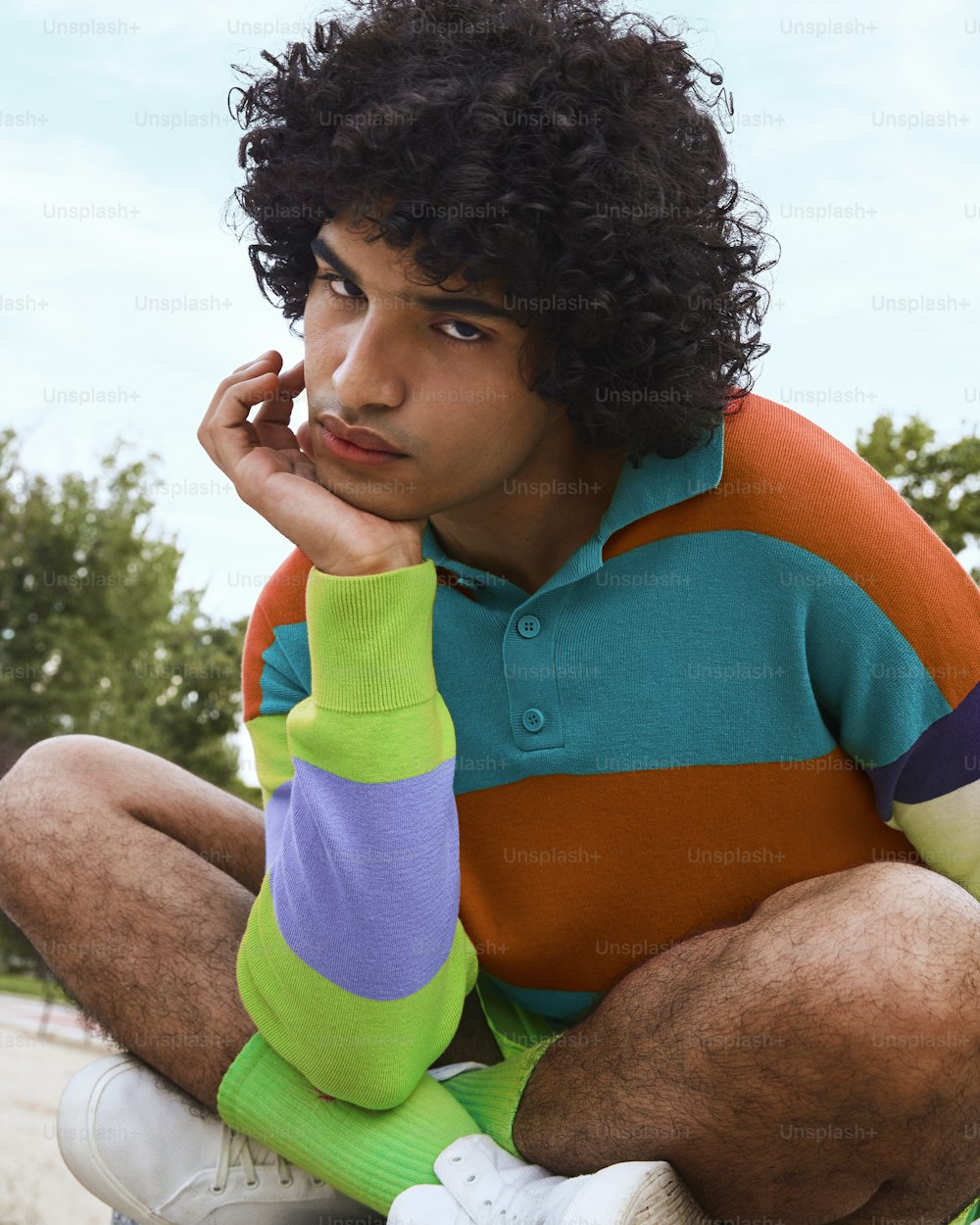 a man with curly hair sitting on a skateboard