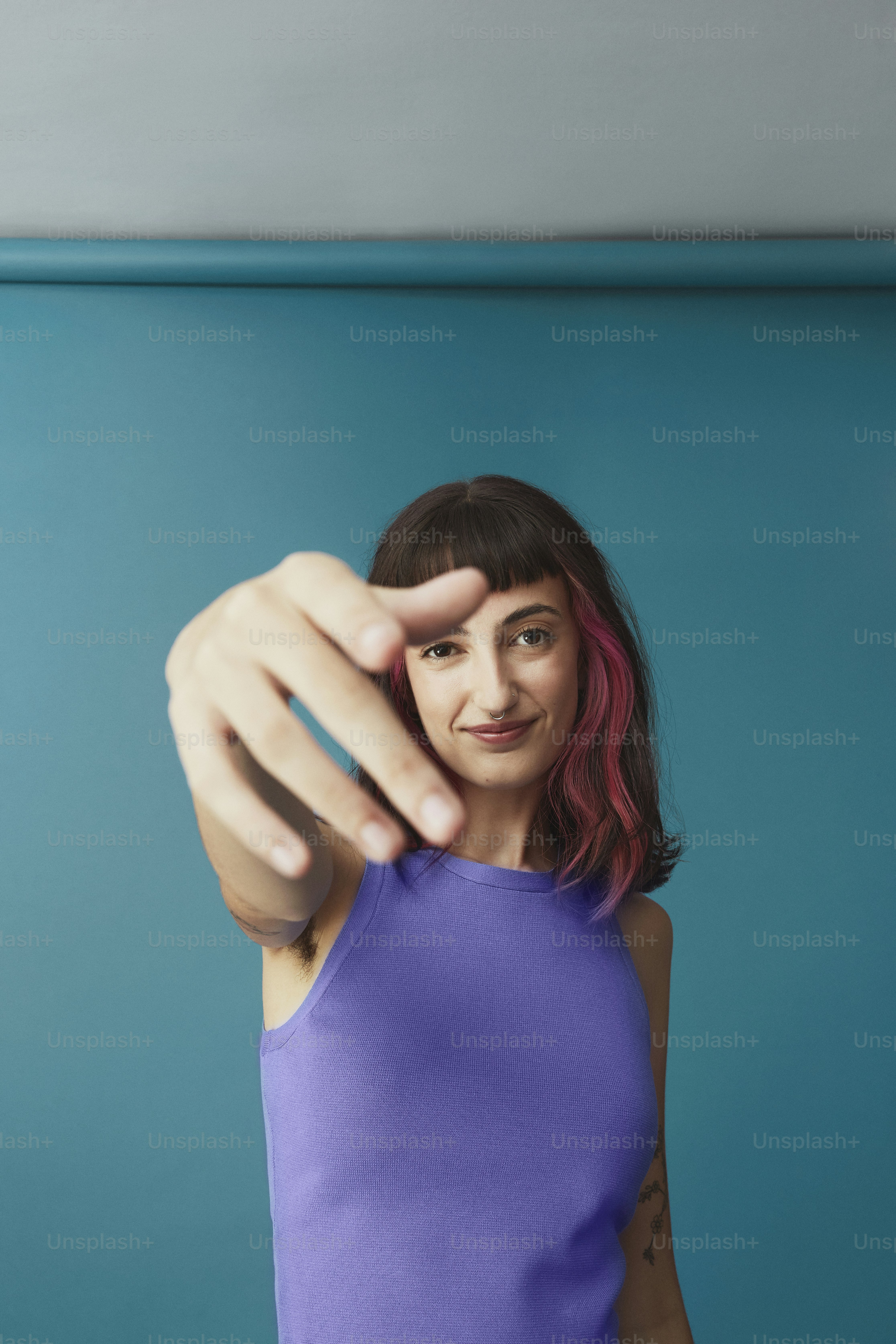Une femme en débardeur violet pointant la caméra