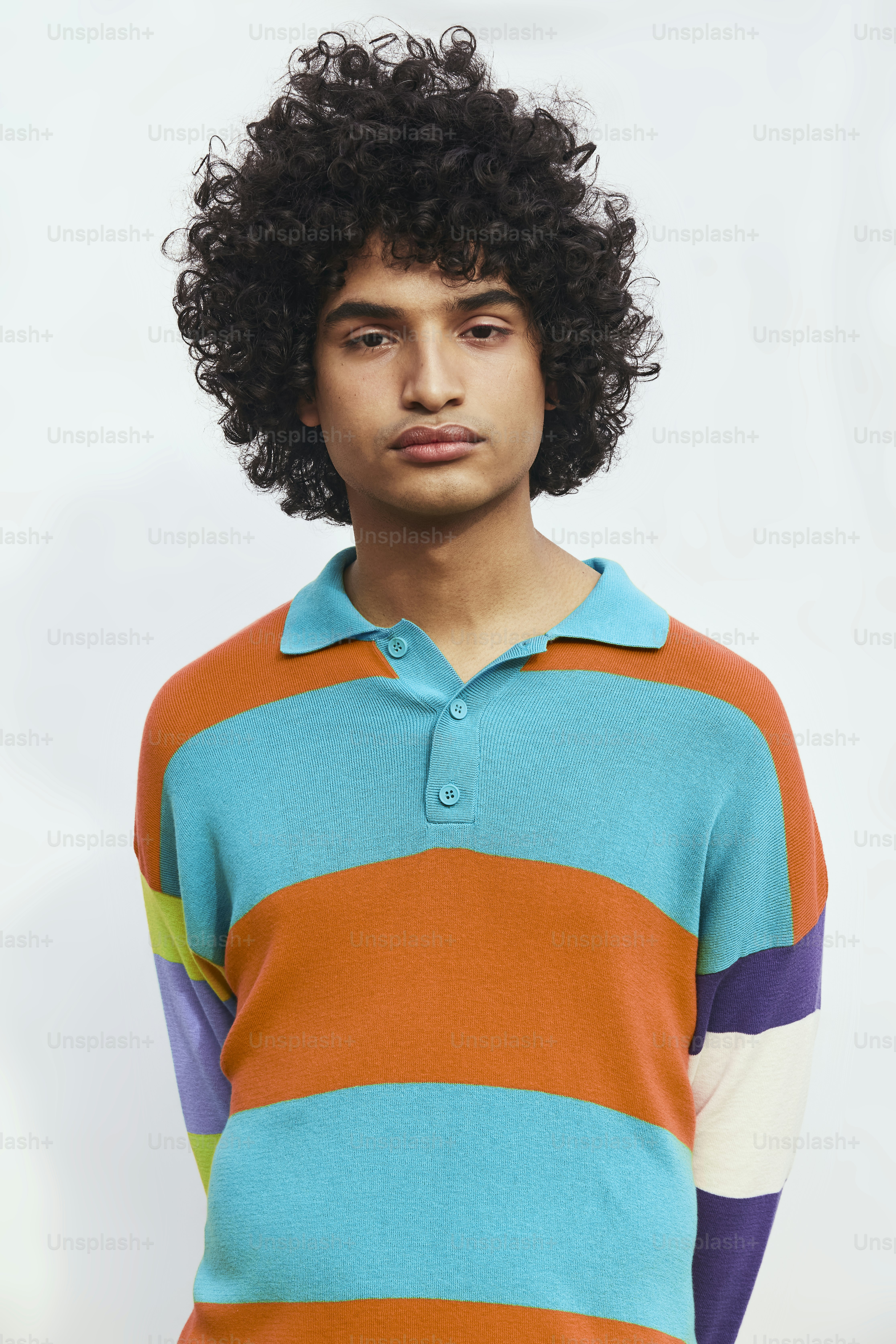 um jovem com cabelo cacheado vestindo uma camisa colorida