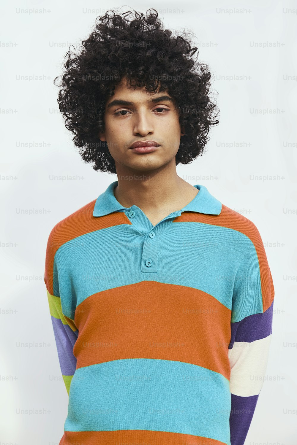 a young man with curly hair wearing a colorful shirt