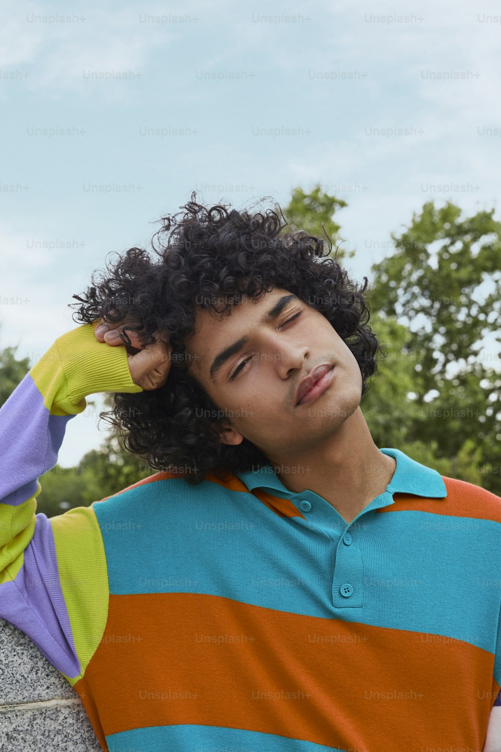 a man with curly hair wearing a colorful shirt