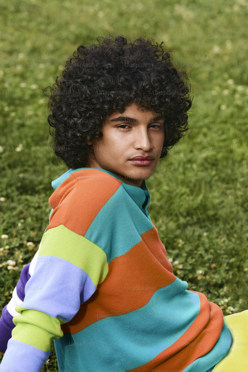 a young man sitting in the grass with a frisbee