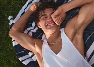 a man laying on top of a blanket on top of a green field