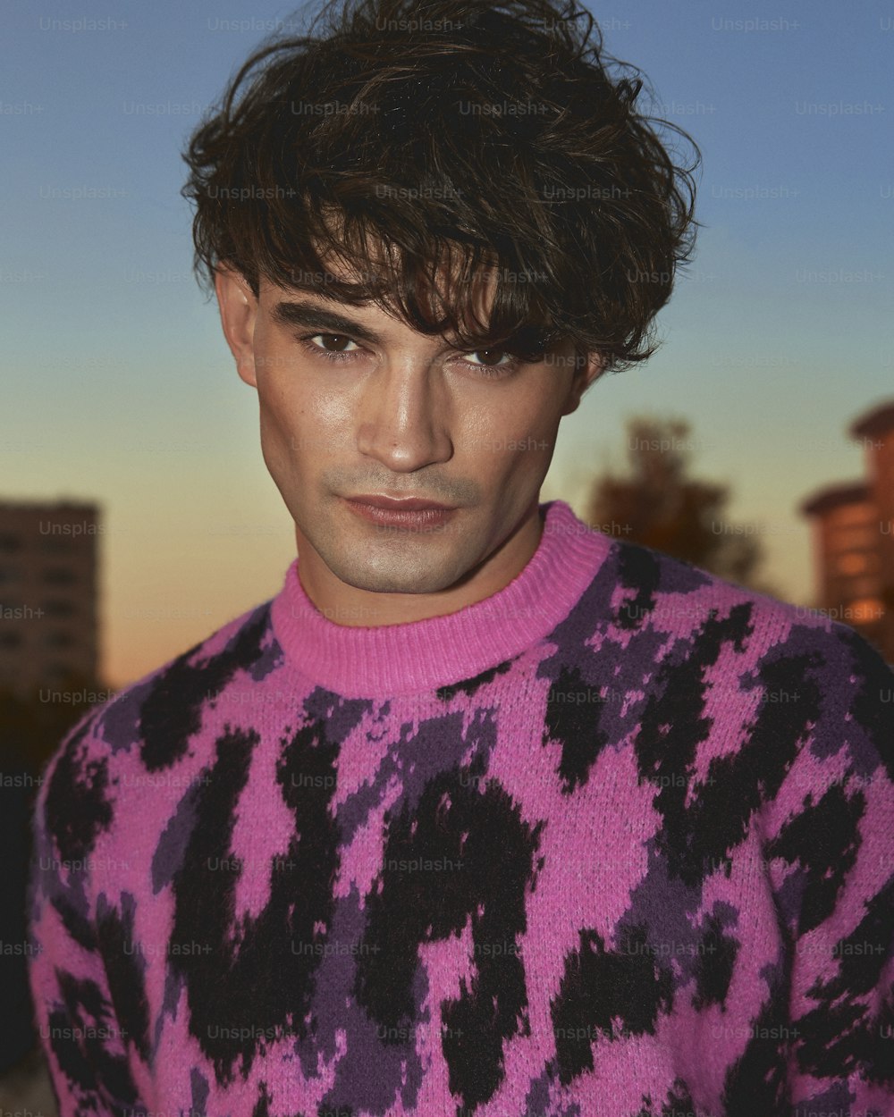a man in a pink and black sweater looking at the camera