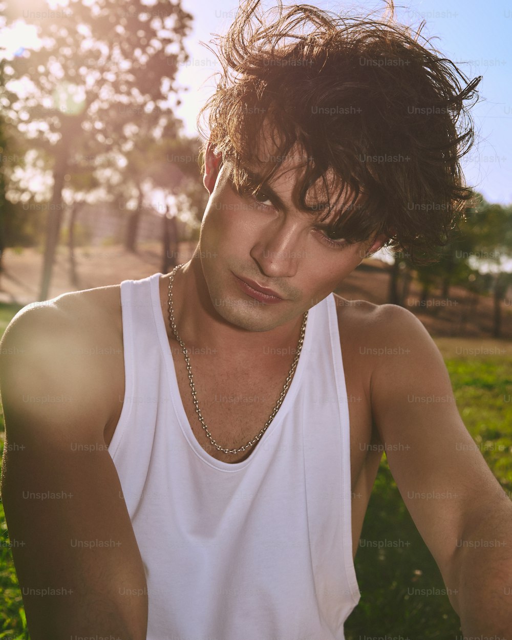 a man in a white tank top sitting in the grass