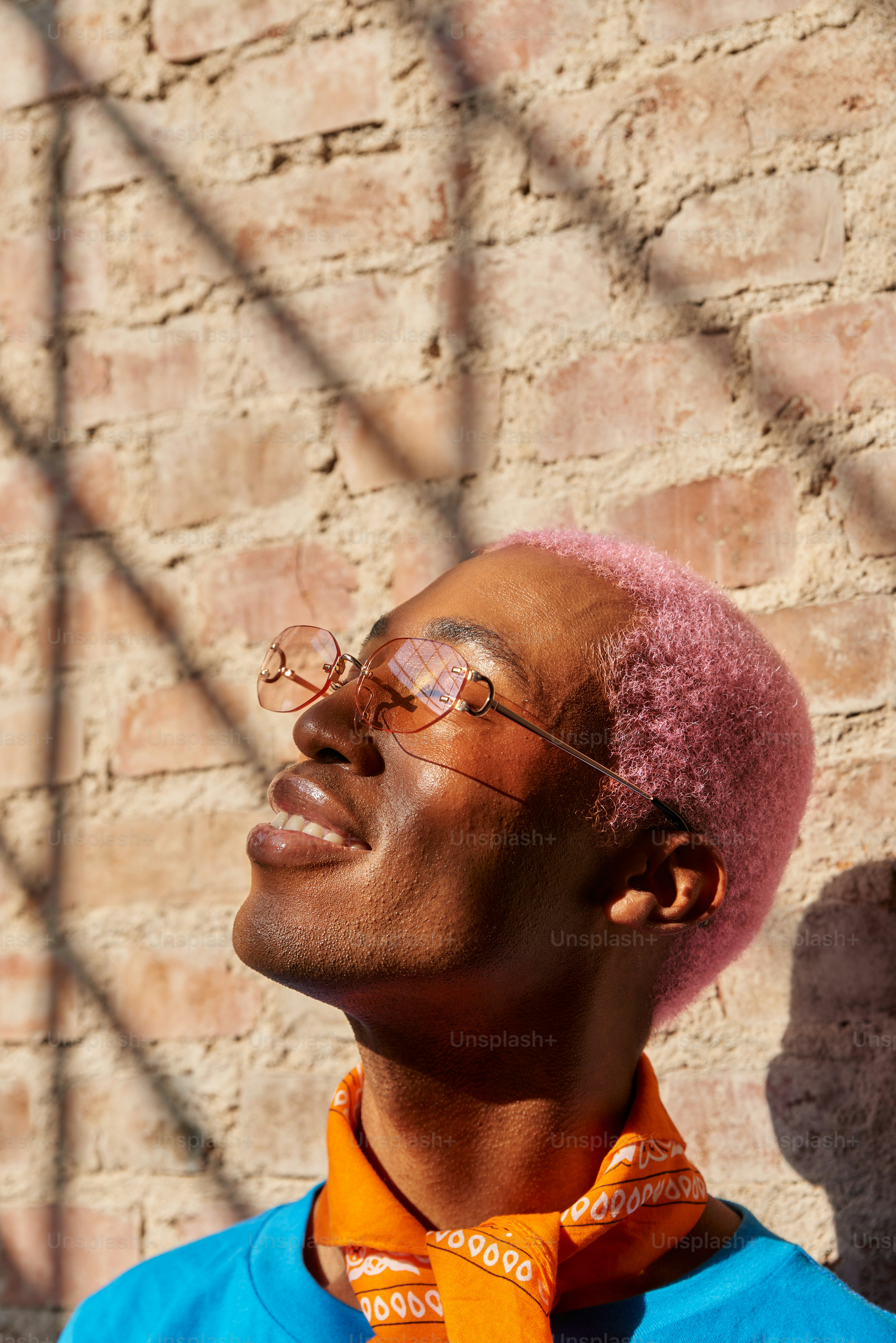 Un uomo con i capelli rosa che indossa occhiali e una camicia blu