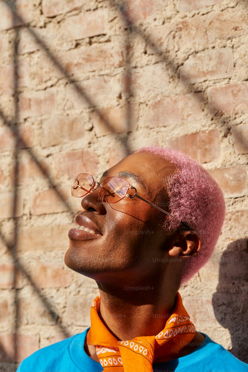 a man with pink hair wearing glasses and a blue shirt