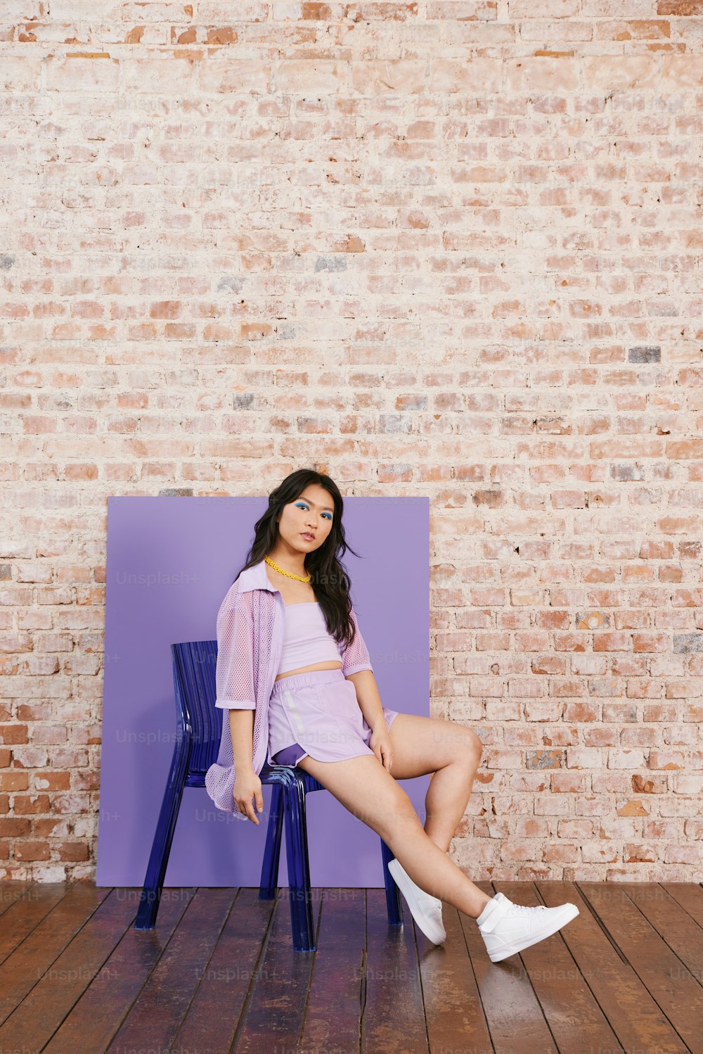 Una mujer sentada en una silla frente a una pared de ladrillos