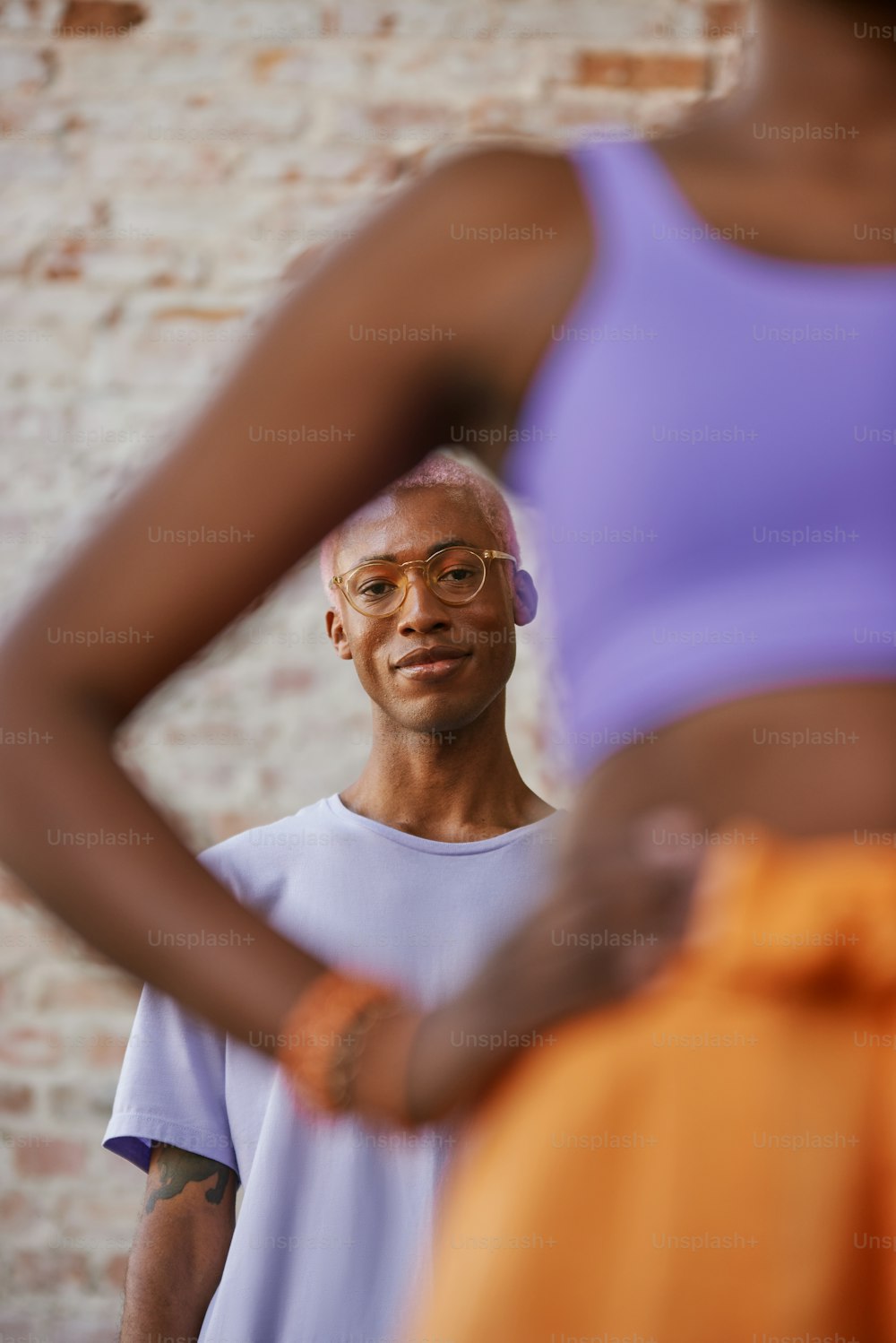 Ein Mann mit Brille, der vor einer Ziegelmauer steht