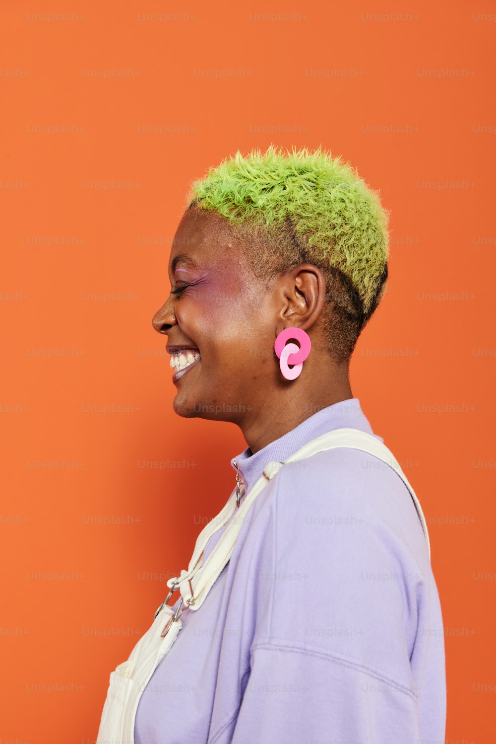 a woman with green hair and pink earrings