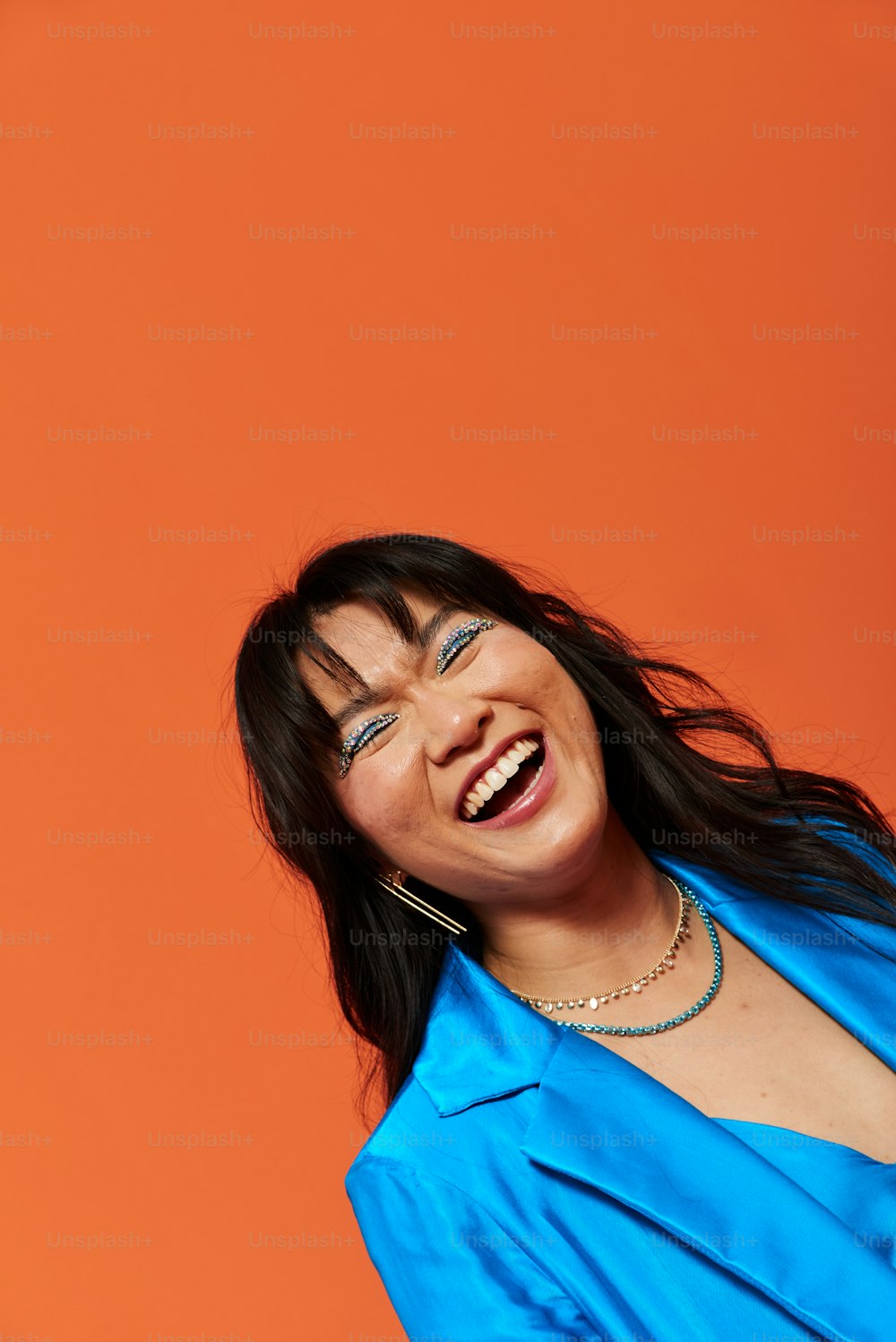 Una donna in una camicia blu sorridente e tenendo in mano un telefono cellulare