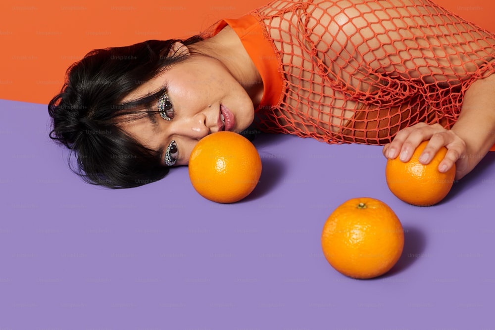 a woman laying on the ground with three oranges
