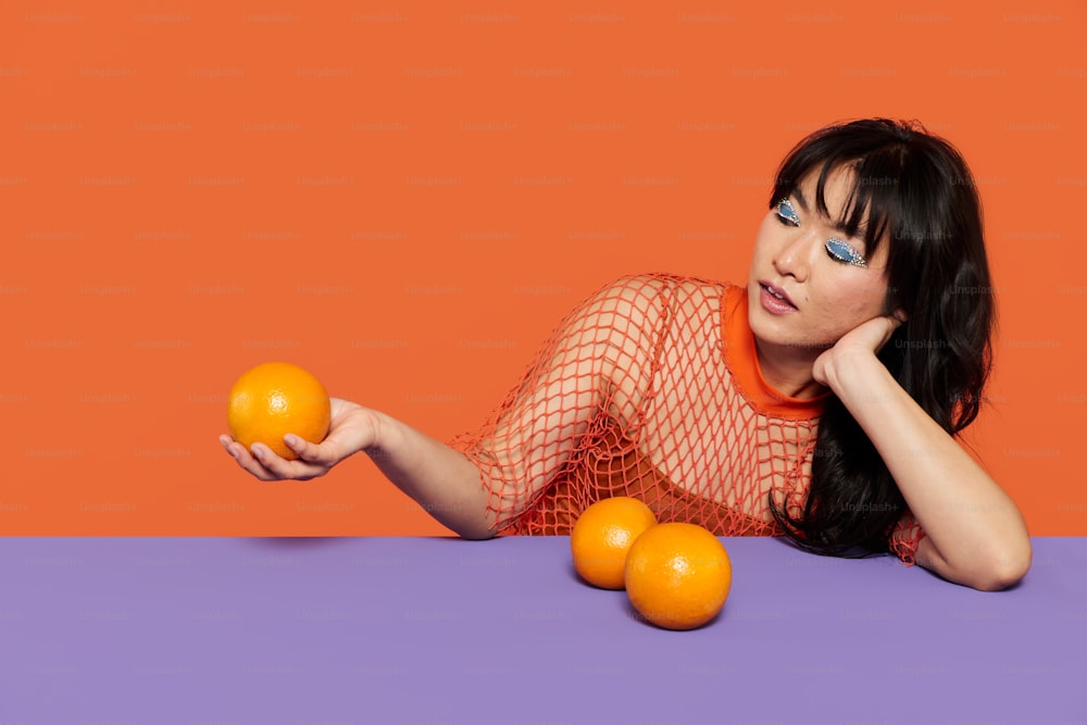 Eine Frau, die mit Orangen auf einem Tisch liegt