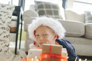 a little boy wearing a santa hat sitting in front of a birthday cake