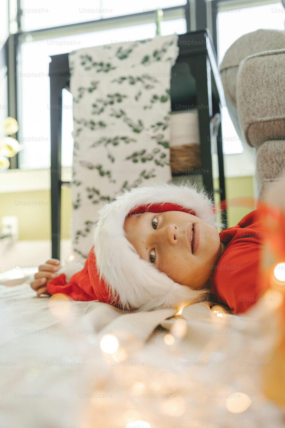a young child laying on the floor wearing a santa hat