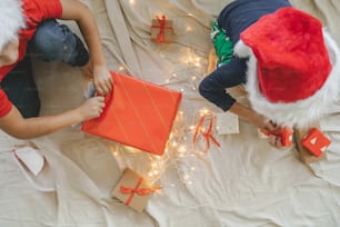 two people in santa hats opening presents on a bed