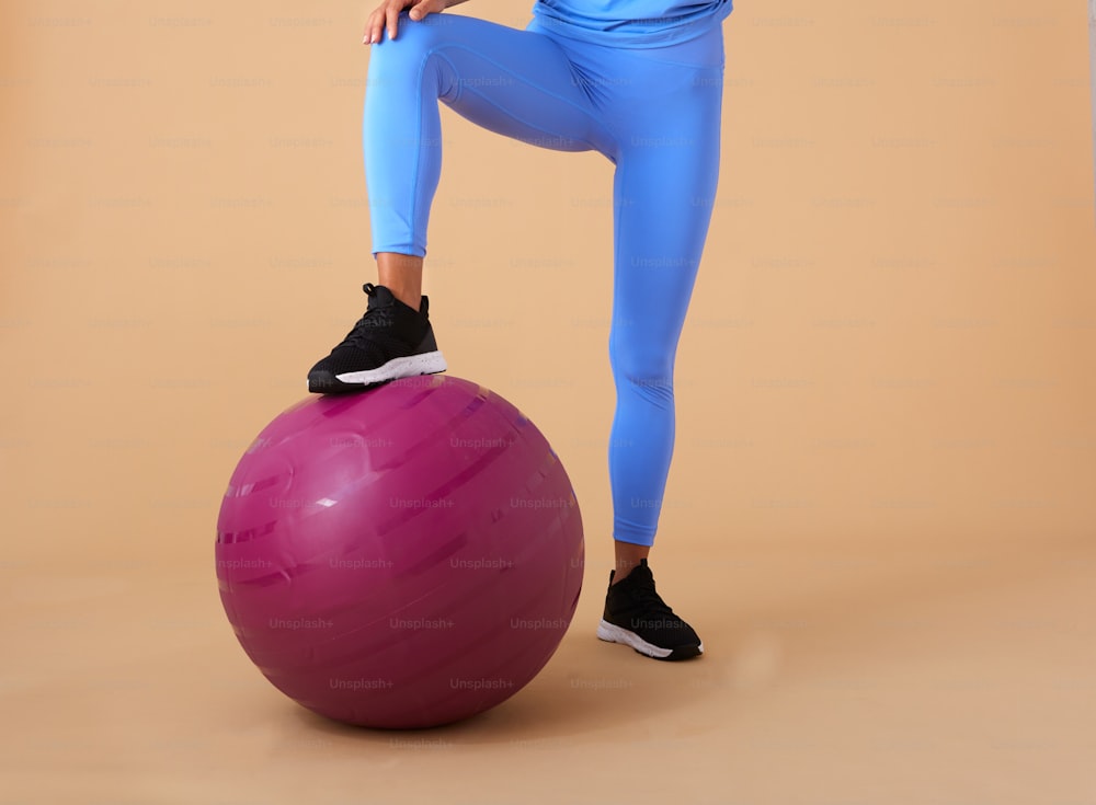 a woman standing on top of a pink ball