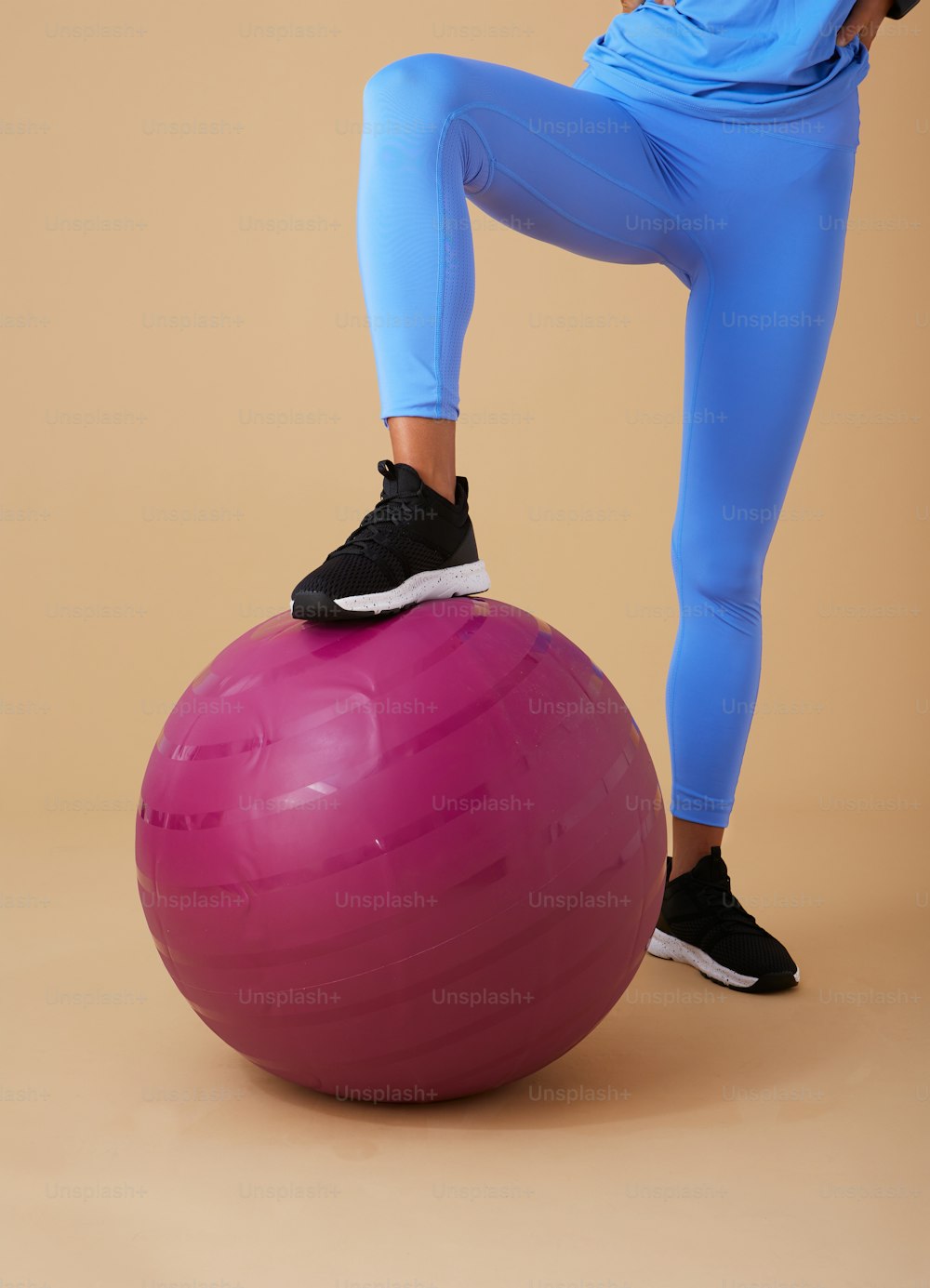 a woman standing on top of a pink exercise ball
