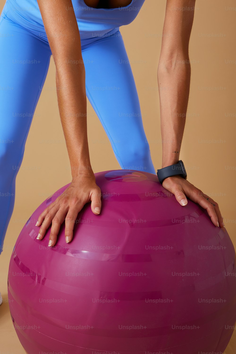 Una donna in un top blu sta facendo esercizi su una palla da ginnastica rosa