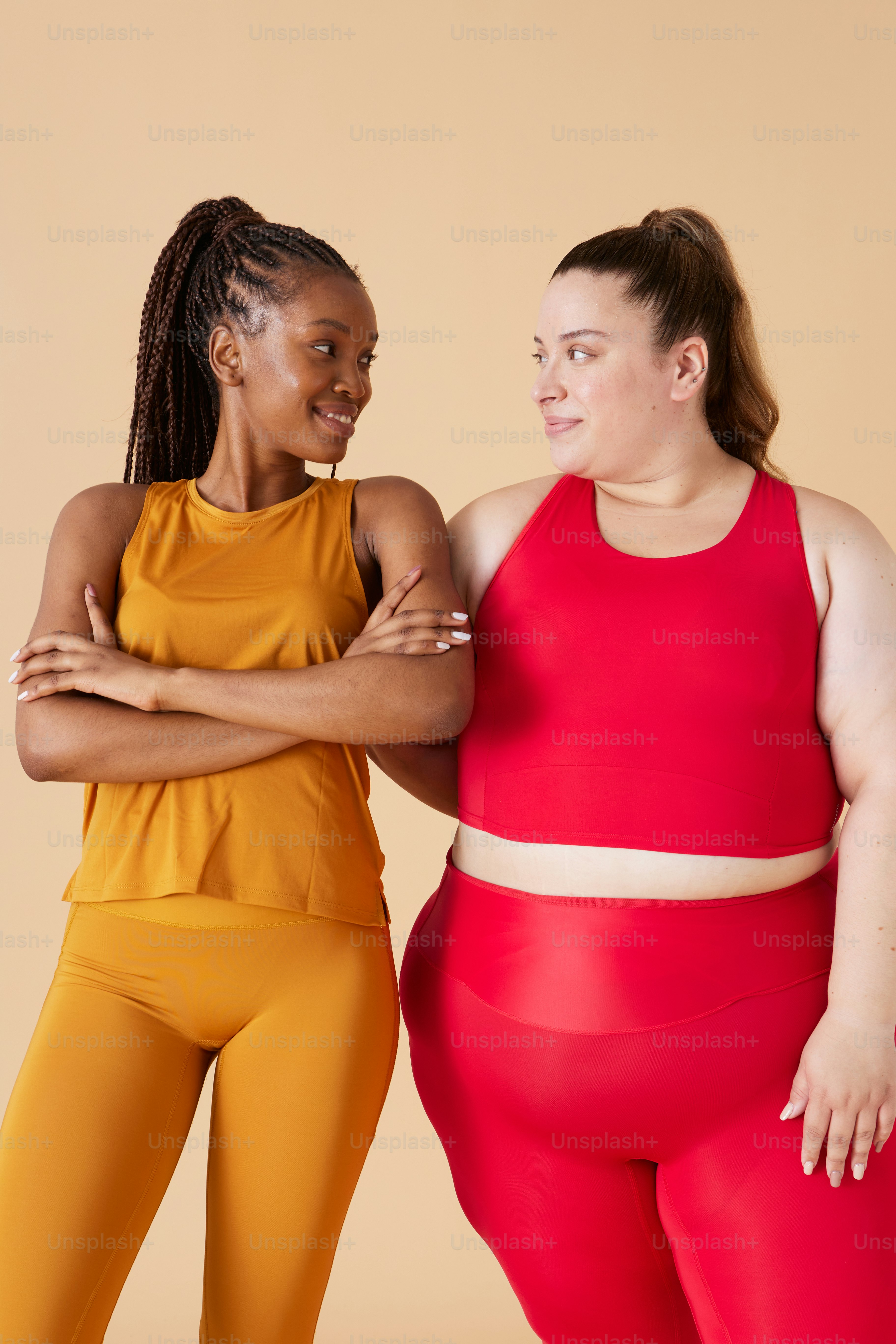 two women standing next to each other with their arms crossed