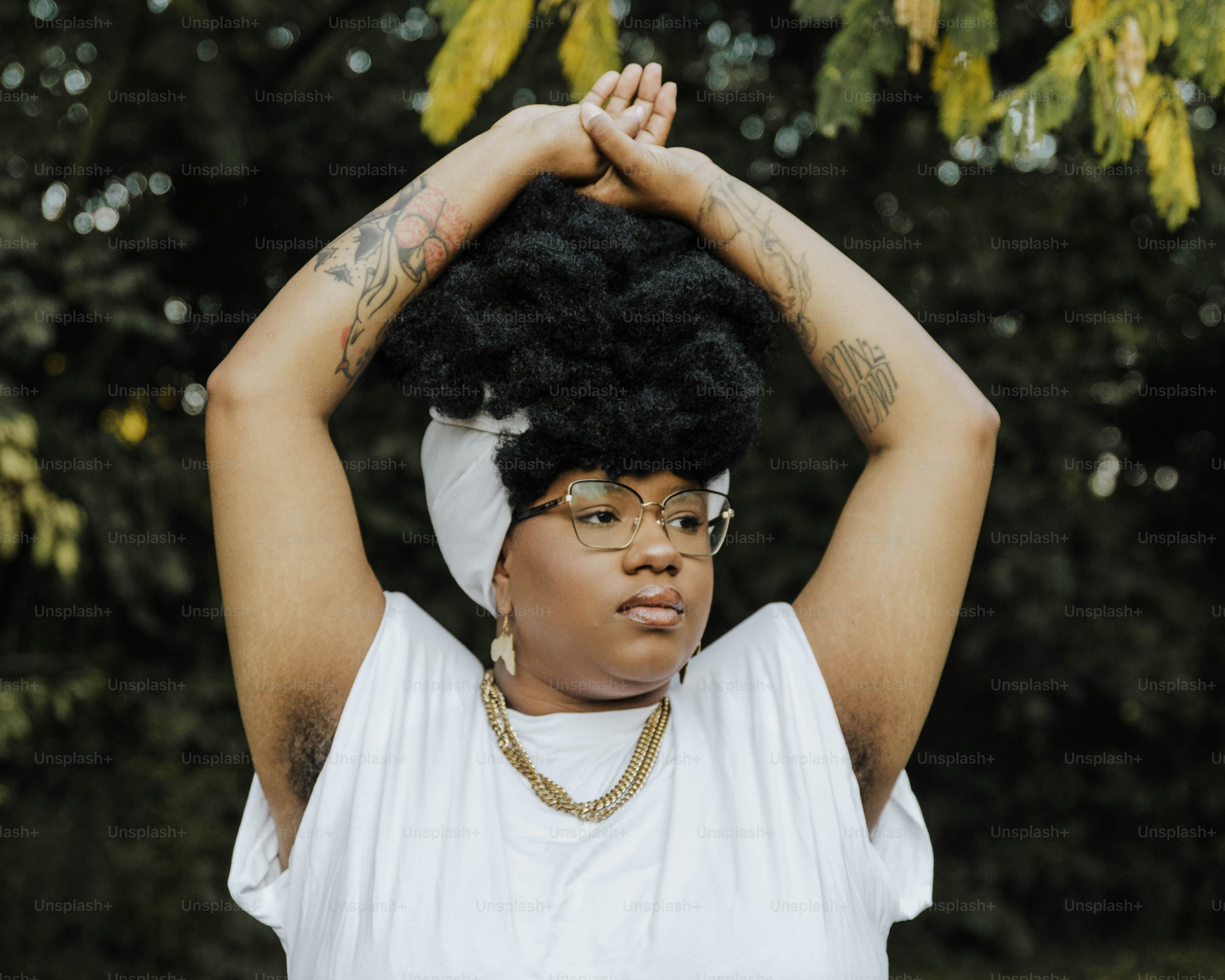 a woman in glasses and a white shirt holds her hands up to her head