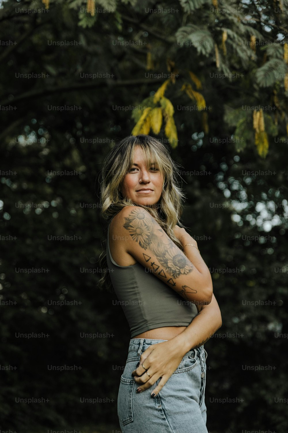 uma mulher em frente a uma árvore com uma tatuagem no braço