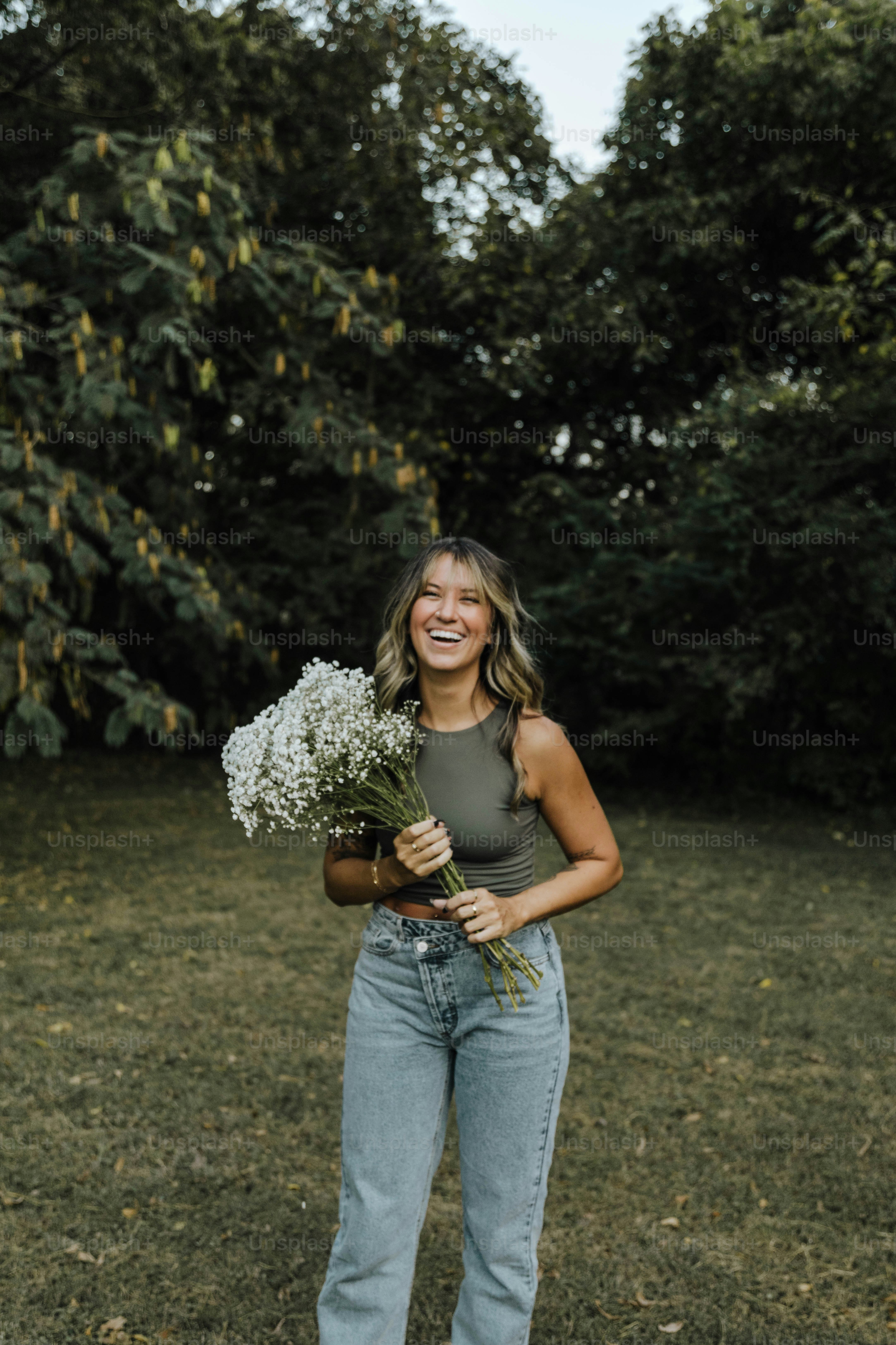 uma mulher em pé em um campo segurando um buquê de flores