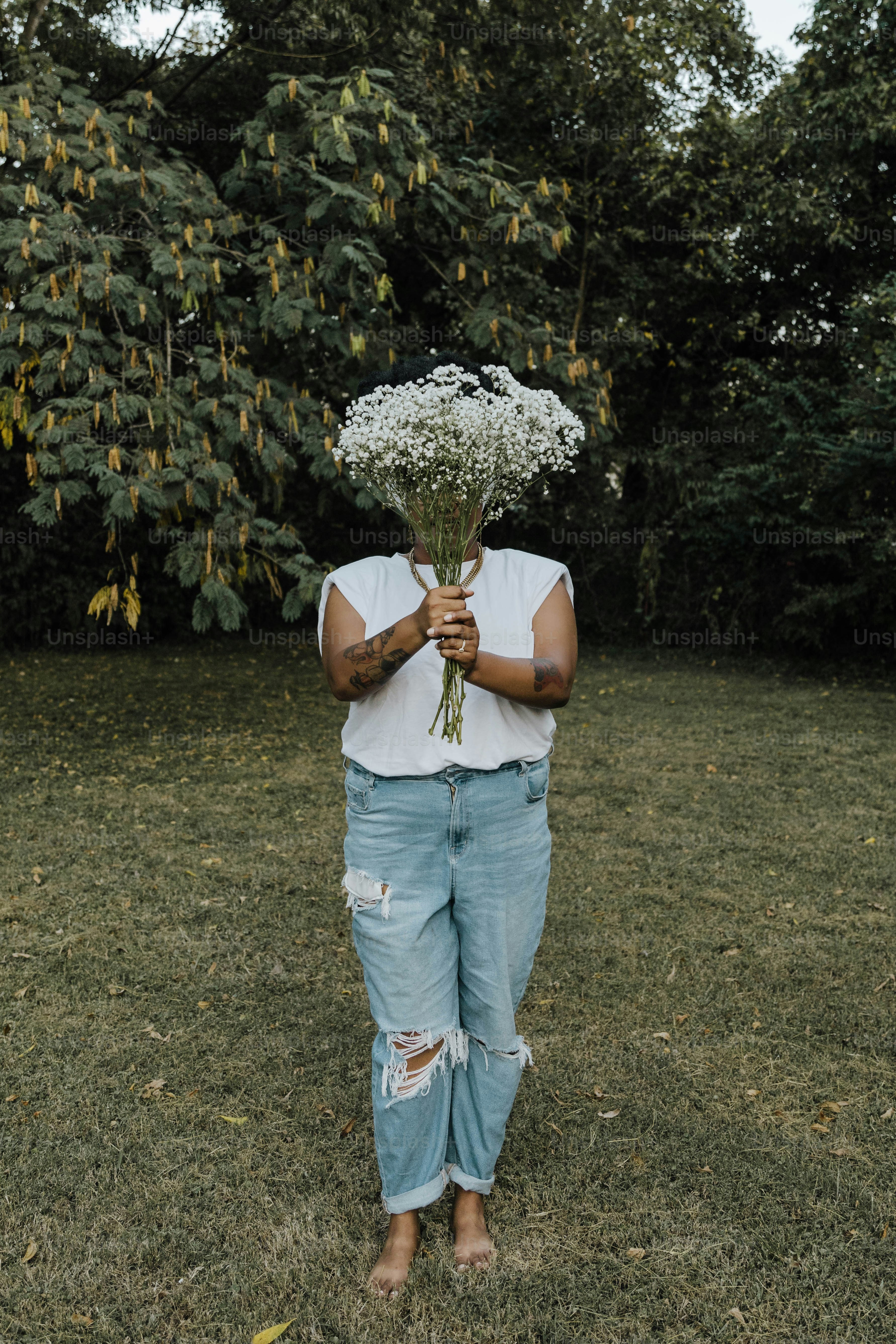 A person standing in a field holding a bunch of flowers photo ...