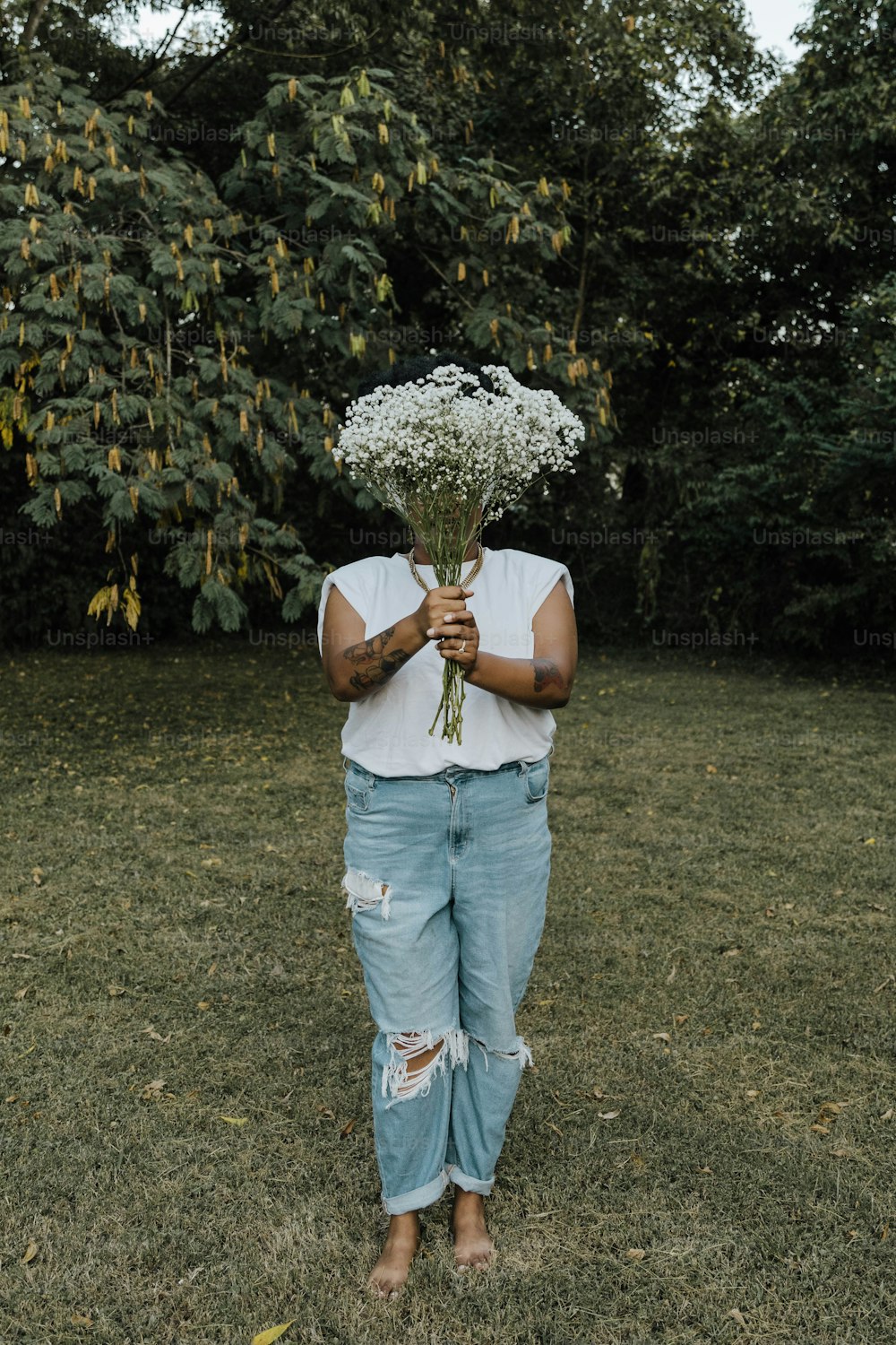 Una persona parada en un campo sosteniendo un ramo de flores