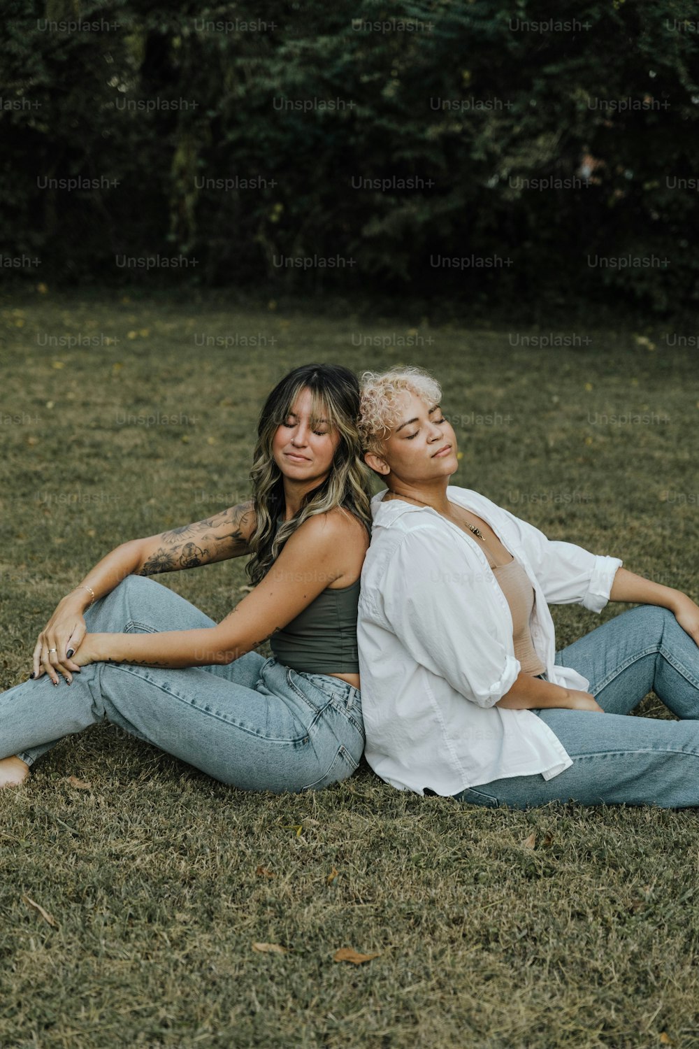 Un couple de femmes assises au sommet d’un champ couvert d’herbe