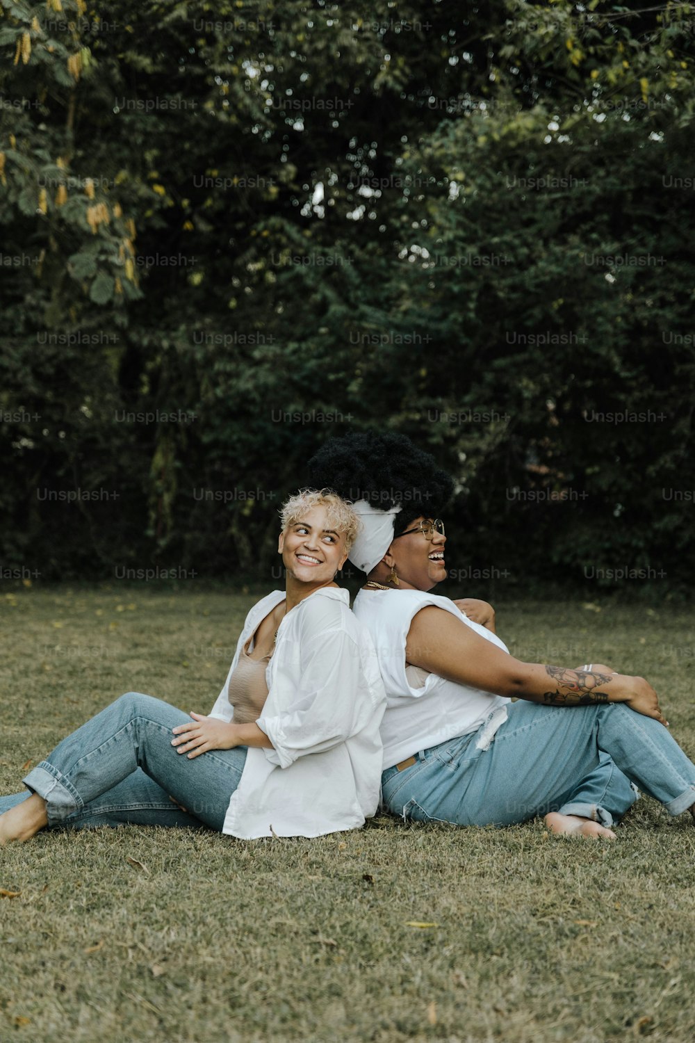 a couple of women sitting on top of a lush green field