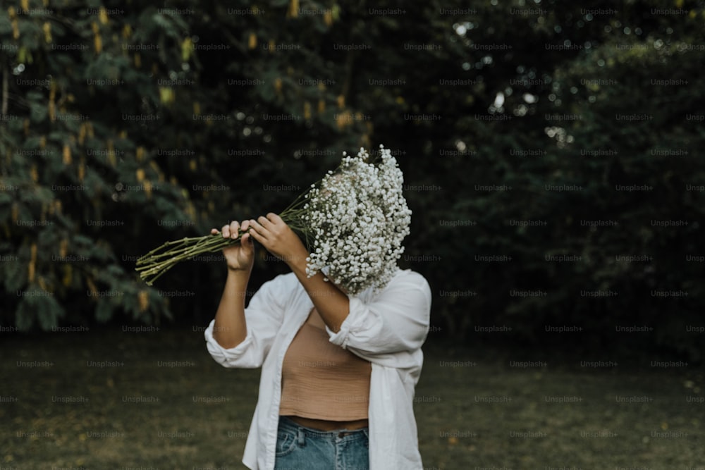 Una mujer sosteniendo un ramo de flores frente a su cara