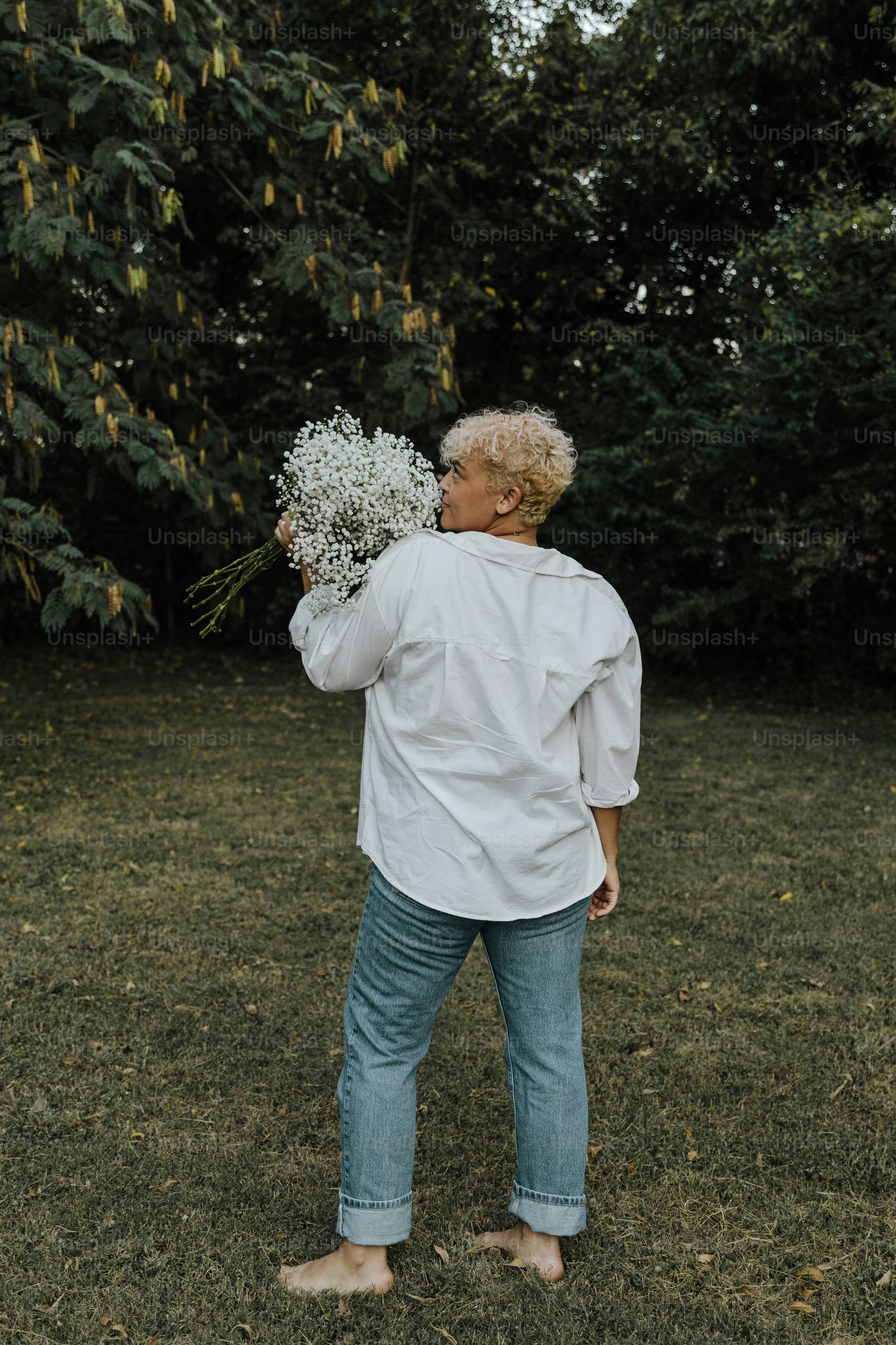 Eine Frau, die auf einem Feld steht und einen Blumenstrauß hält